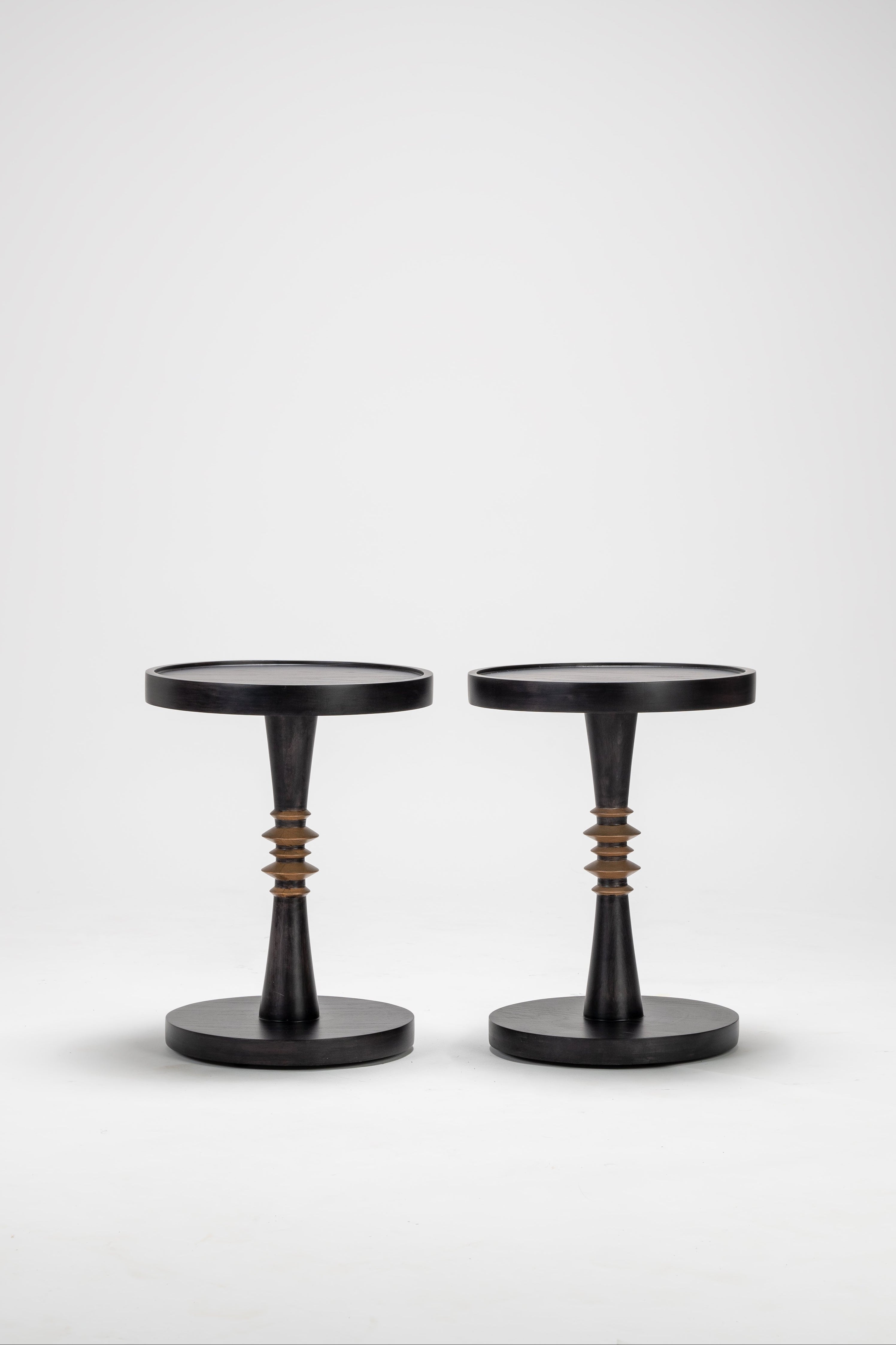 Two black stools with unique designs on a white background