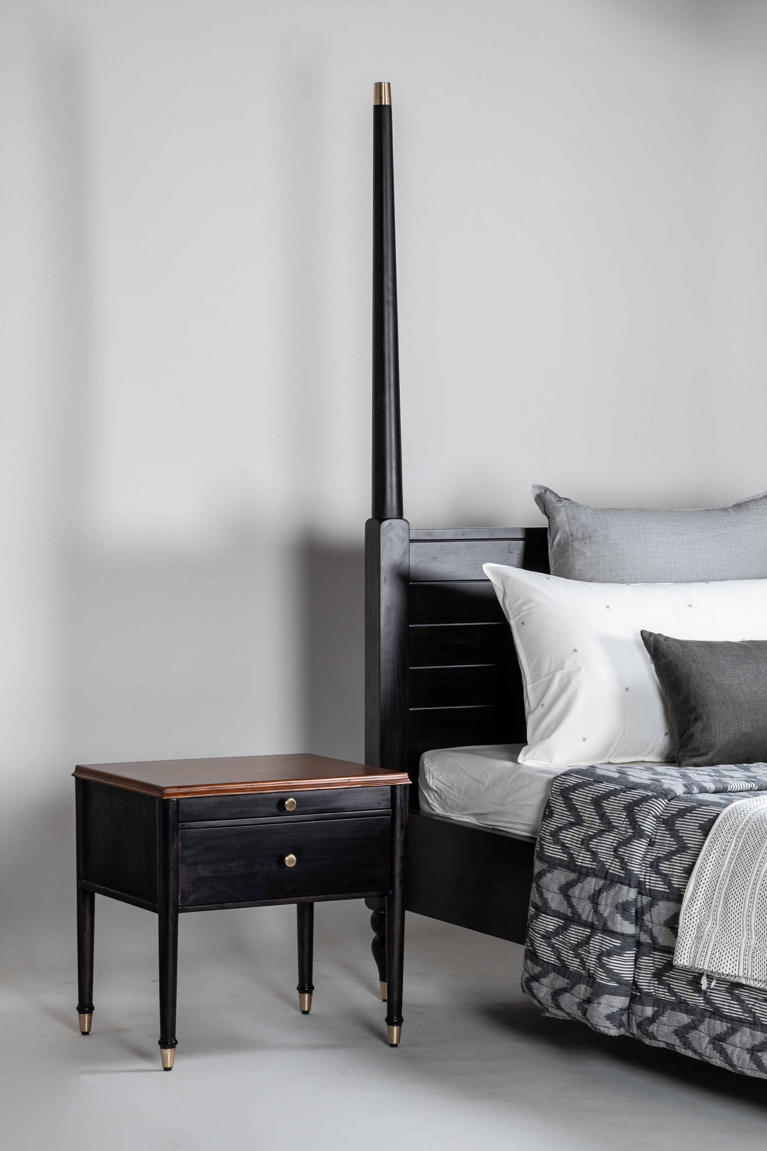 Bedroom with a black bed frame and wooden nightstand against a gray wall.