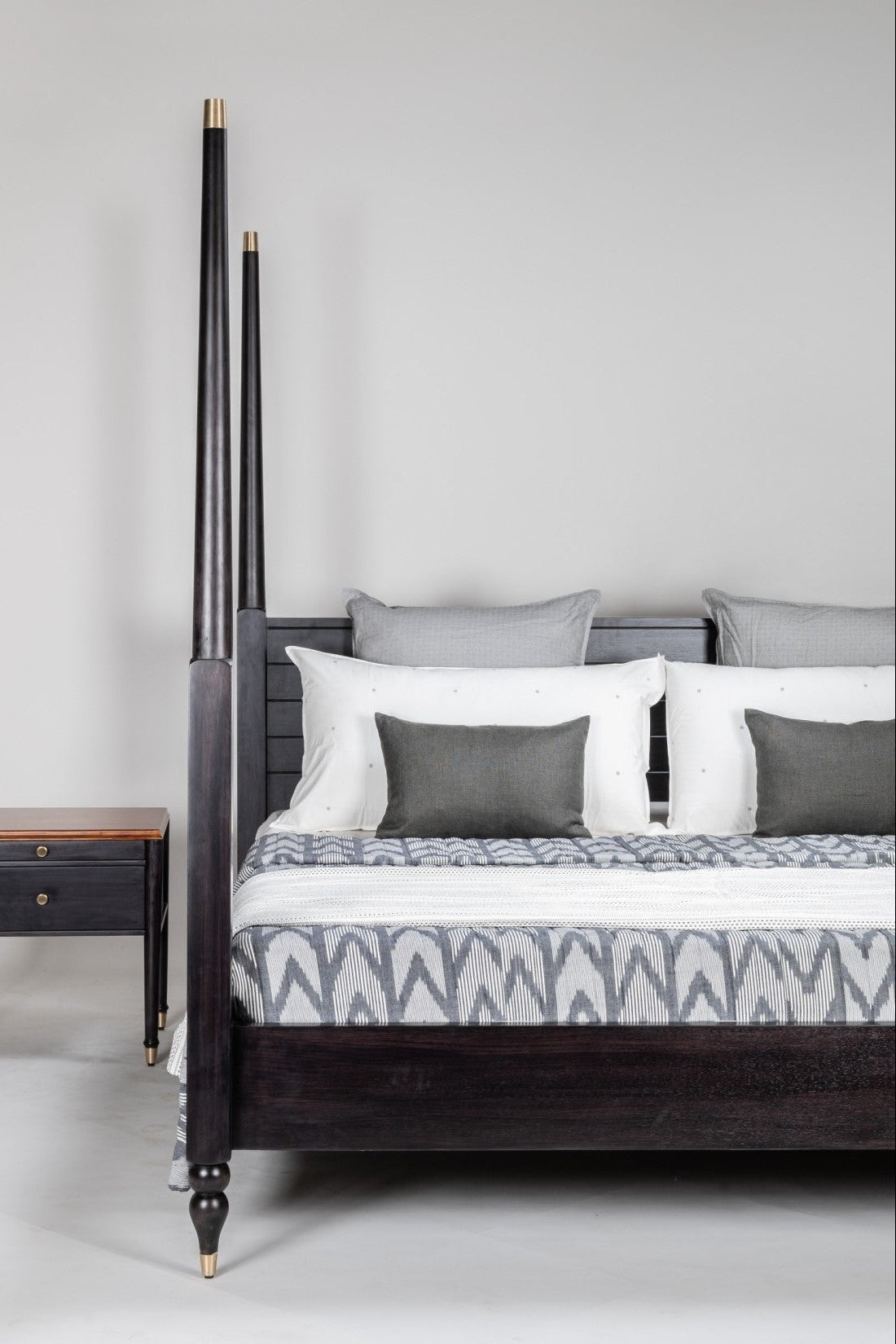 Bedroom with a dark wooden bed and matching nightstand against a light gray wall.