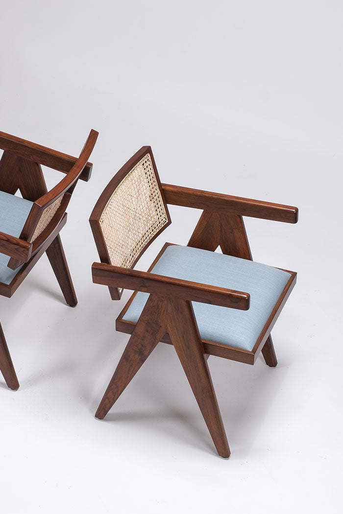 Two wooden chairs with light blue cushions on a white background