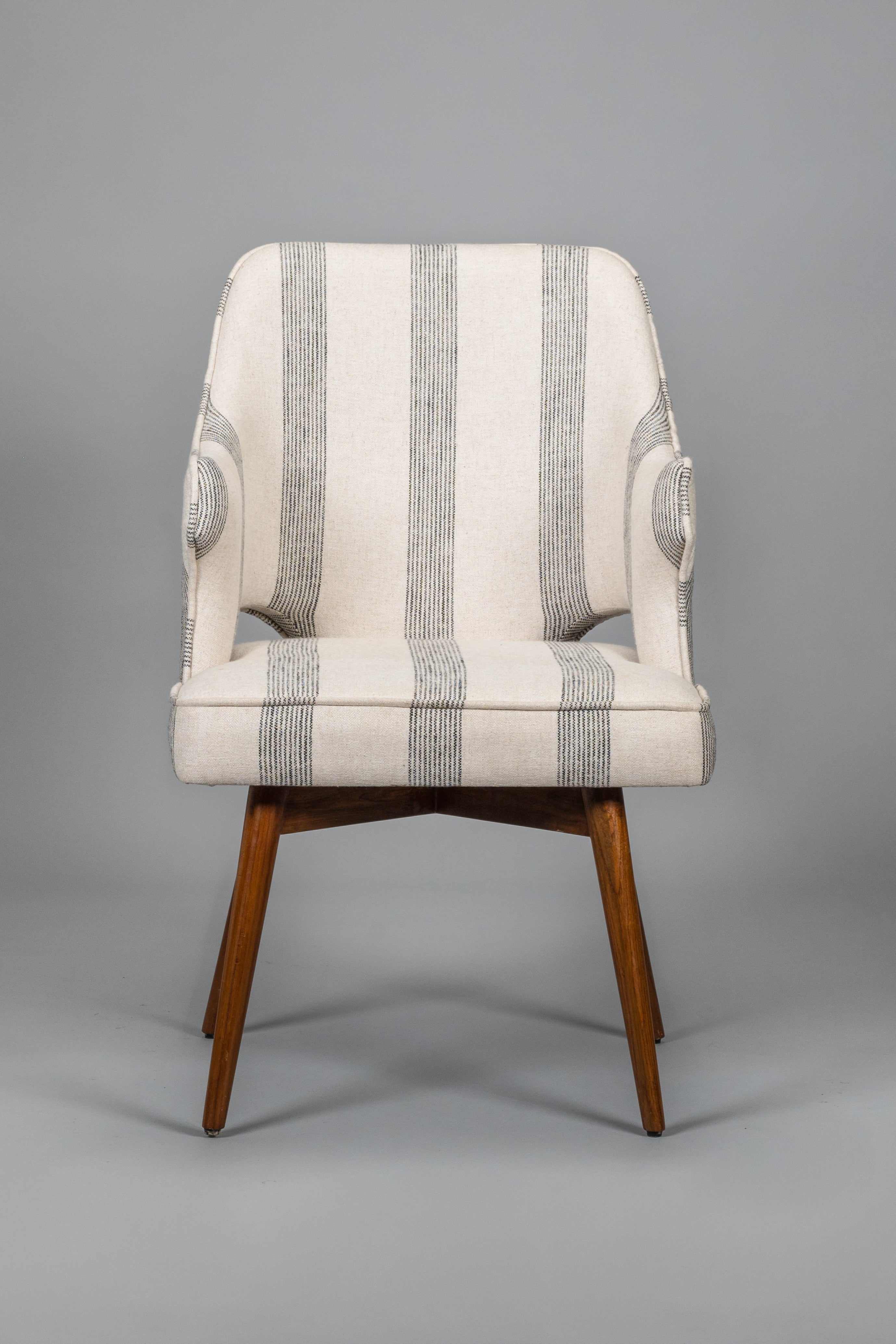 Striped armchair with wooden legs on a gray background