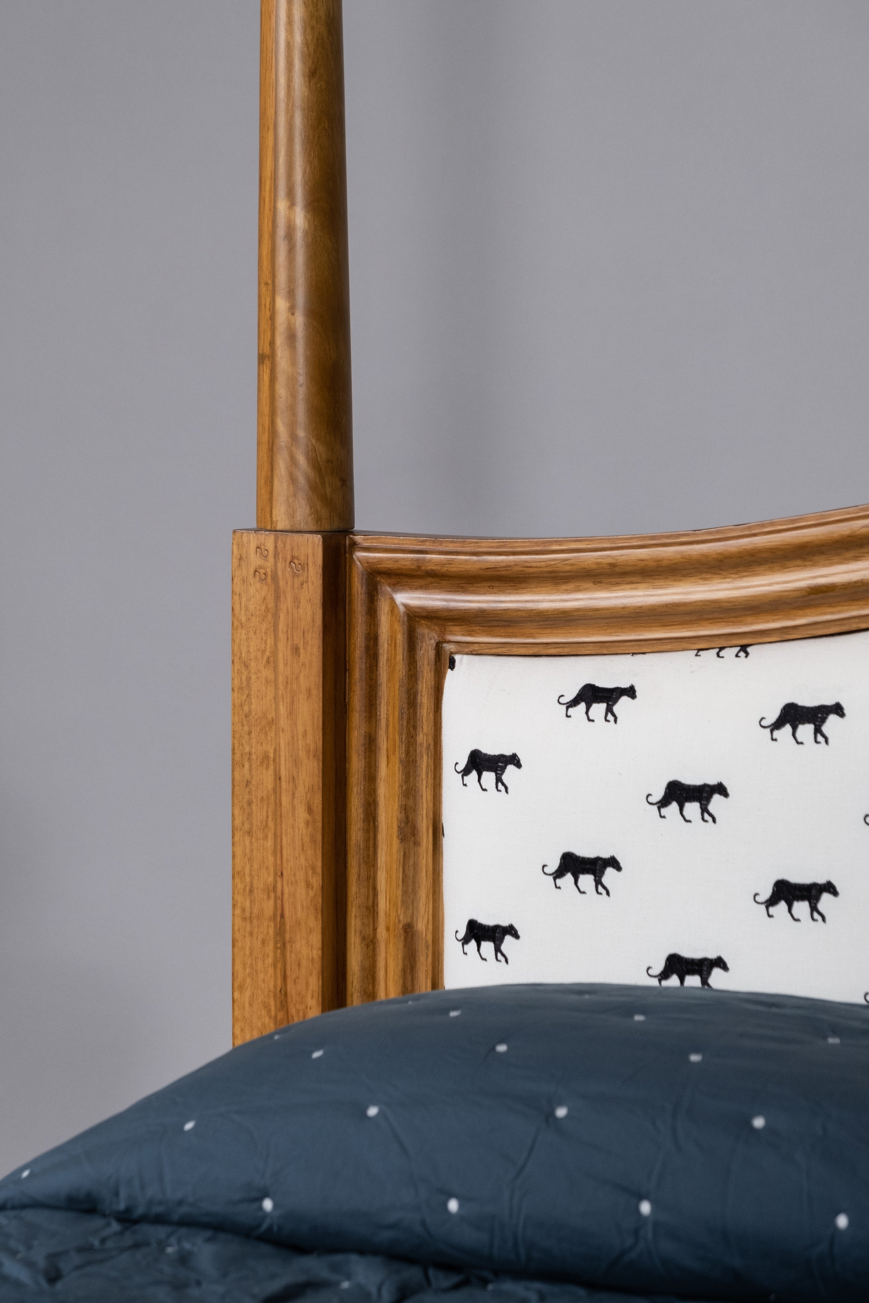 Wooden headboard with a patterned headboard panel featuring black animal silhouettes on a gray wall.