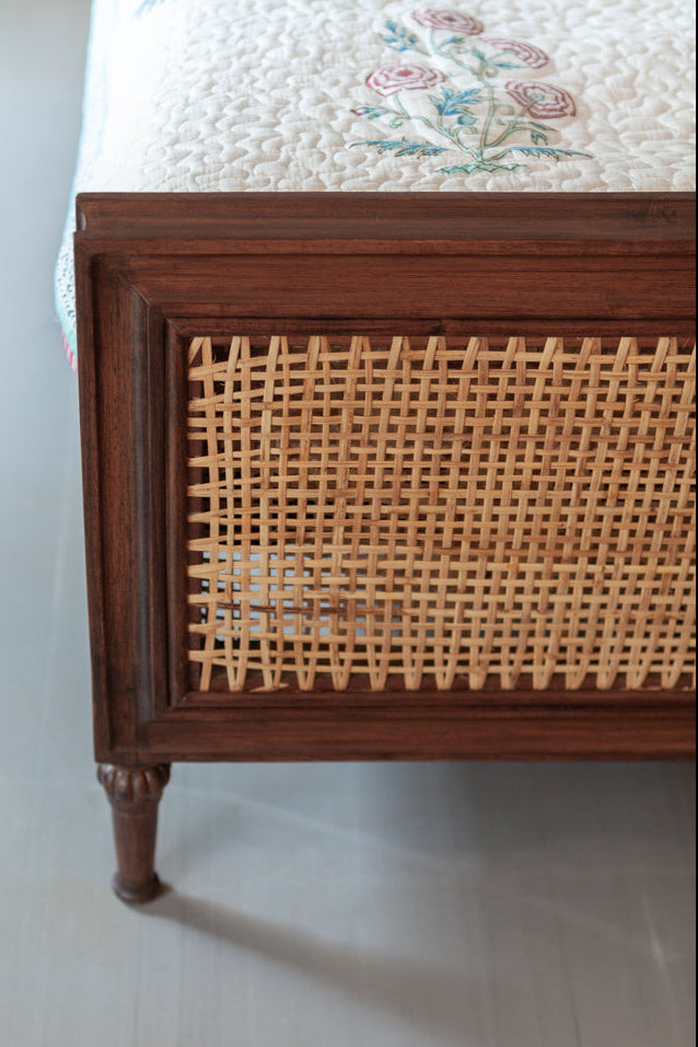 Wooden bed frame with wicker headboard on a white floor