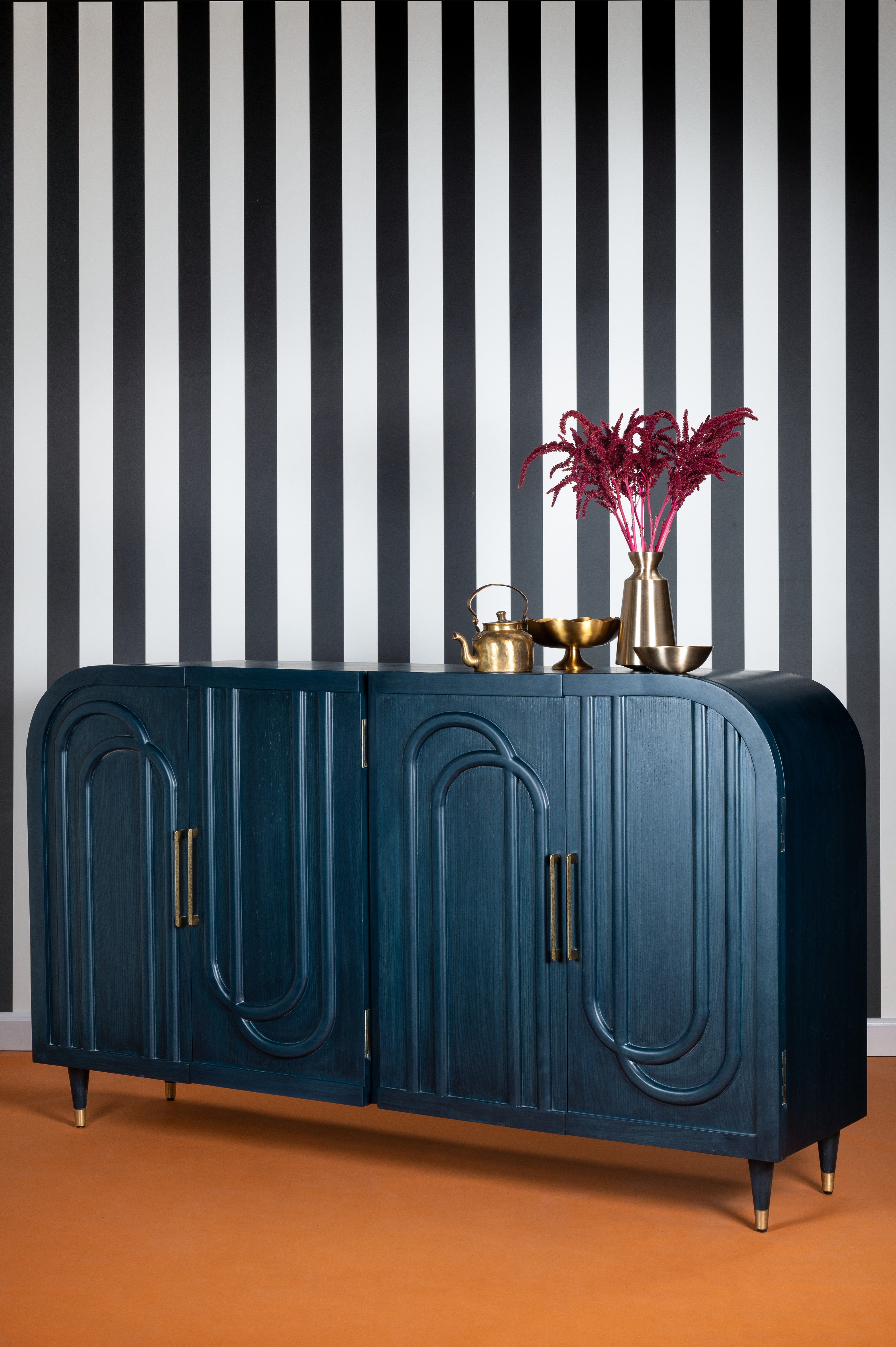 Blue sideboard with decorative items against a black and white striped wall.
