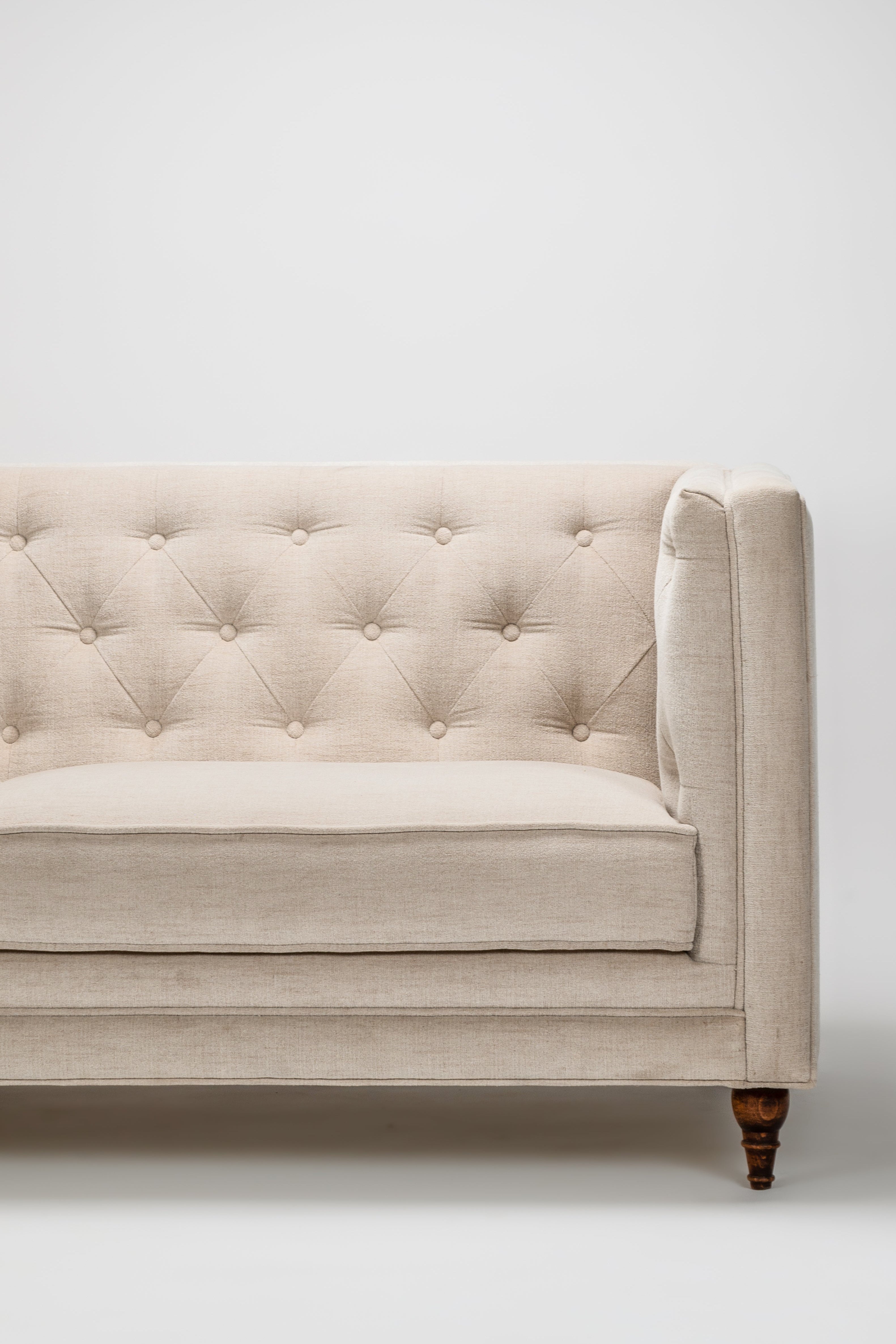 Beige tufted sofa against a white background