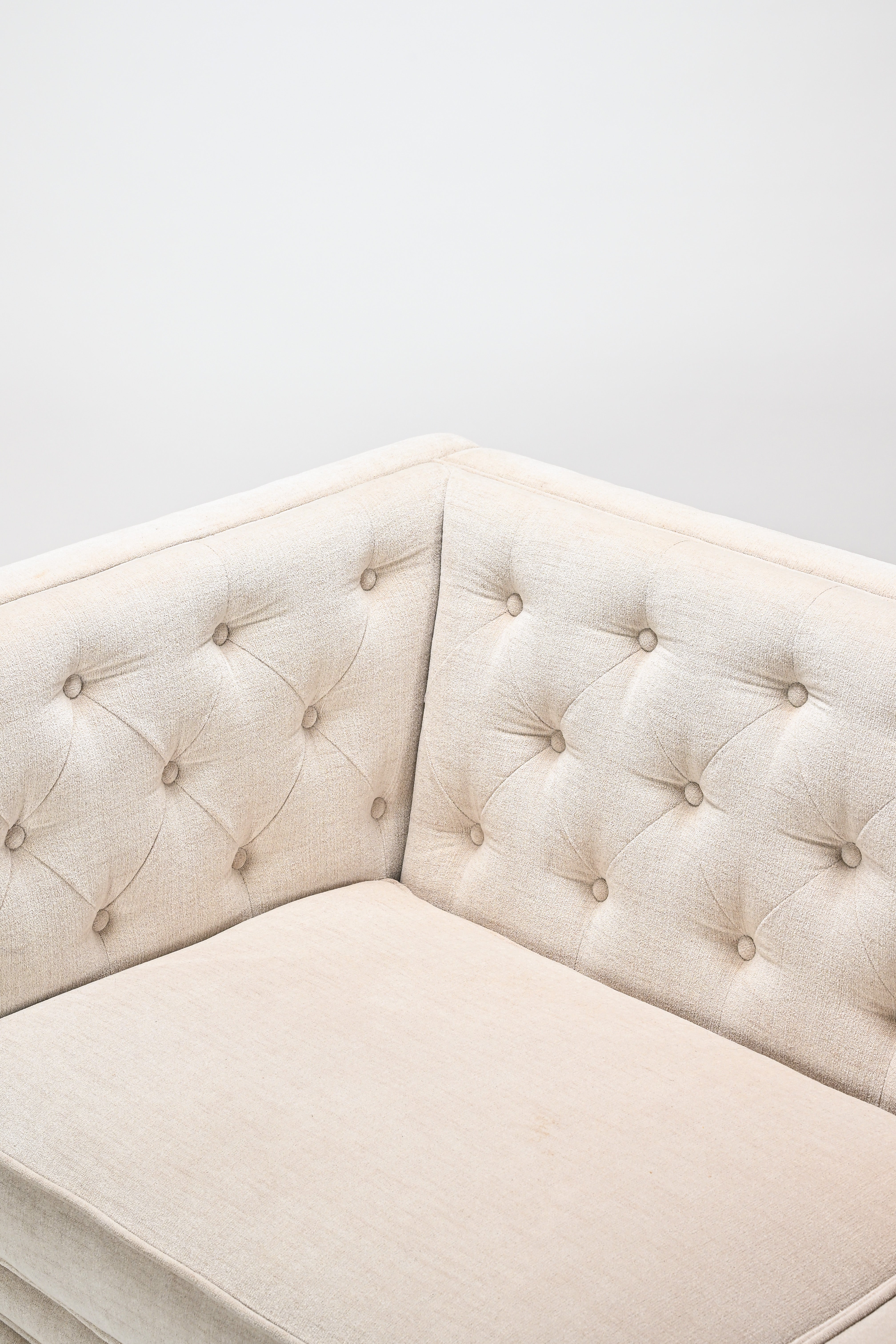 Beige tufted corner bench against a white wall