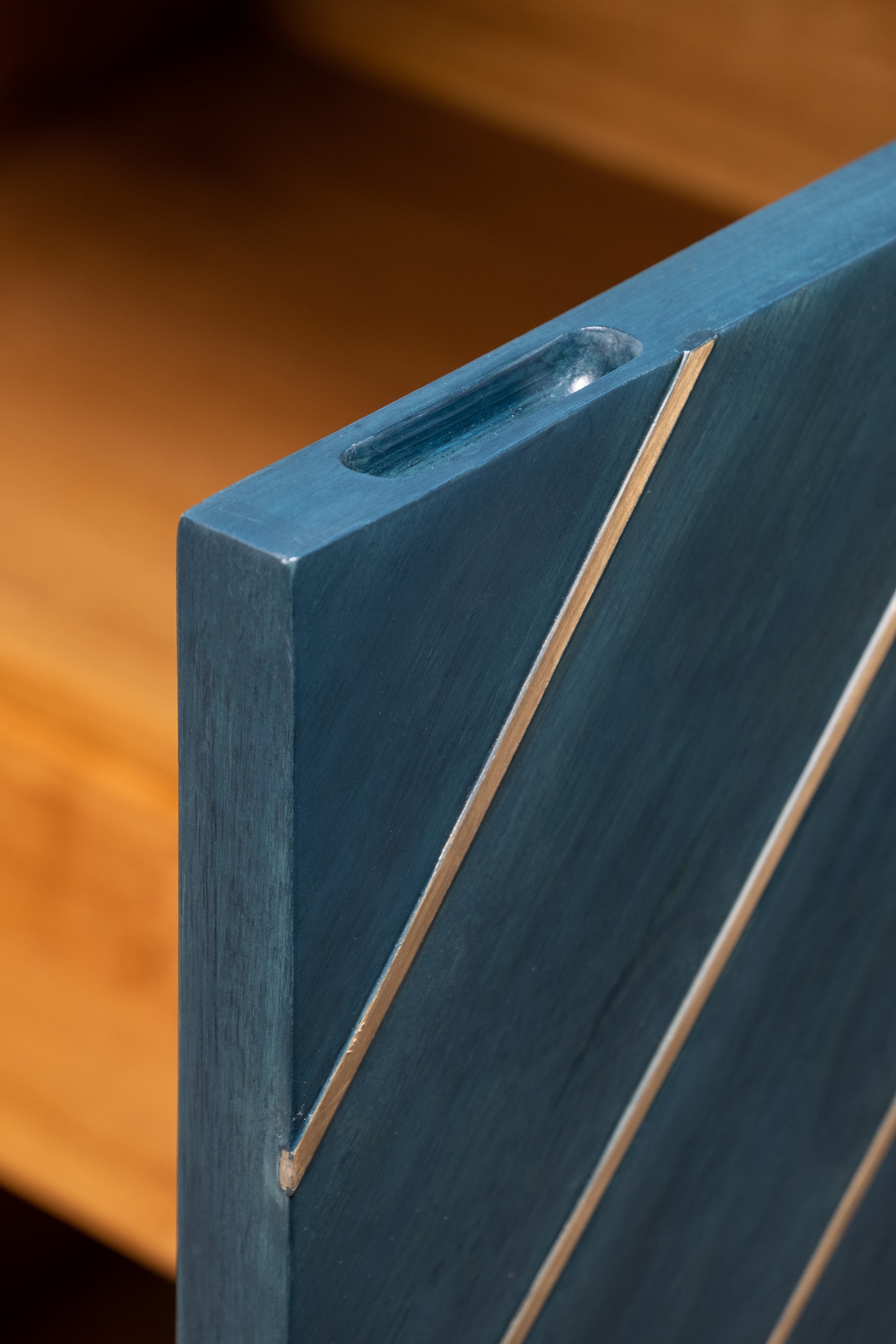Close-up of a blue wooden panel with a visible joint on a wooden surface.