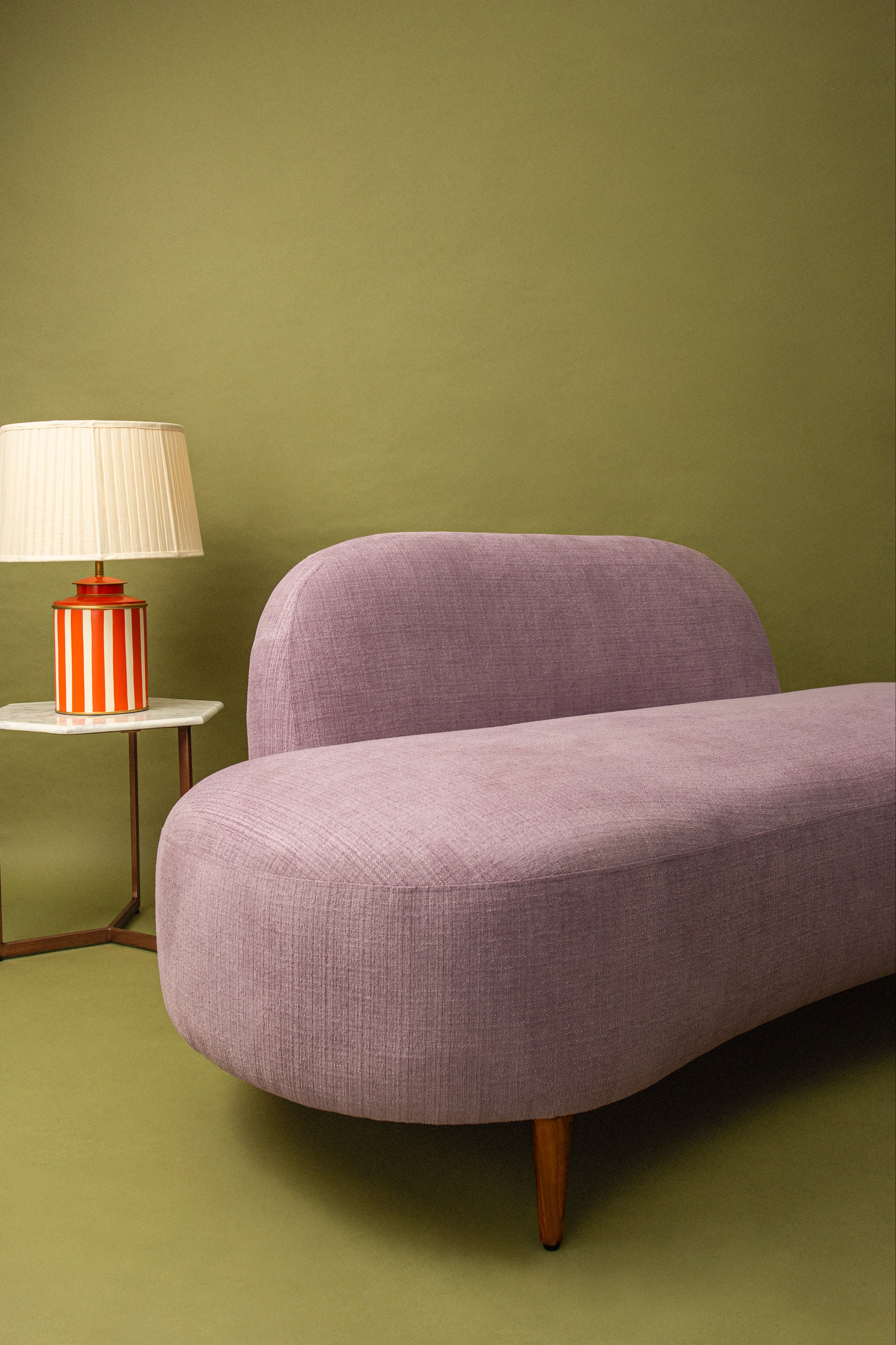 Purple sofa and striped lamp on a green wall