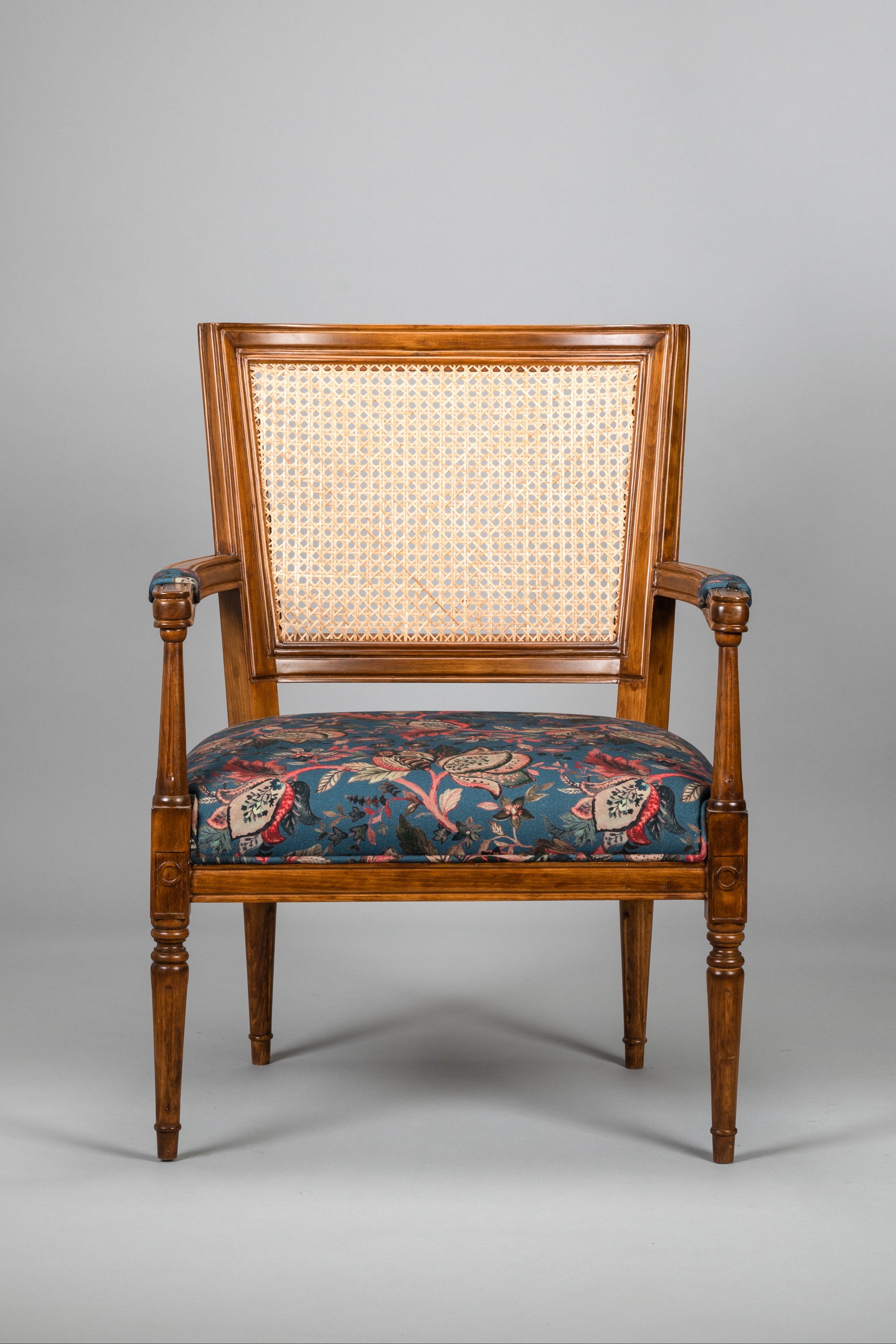Wooden armchair with floral patterned seat on a gray background
