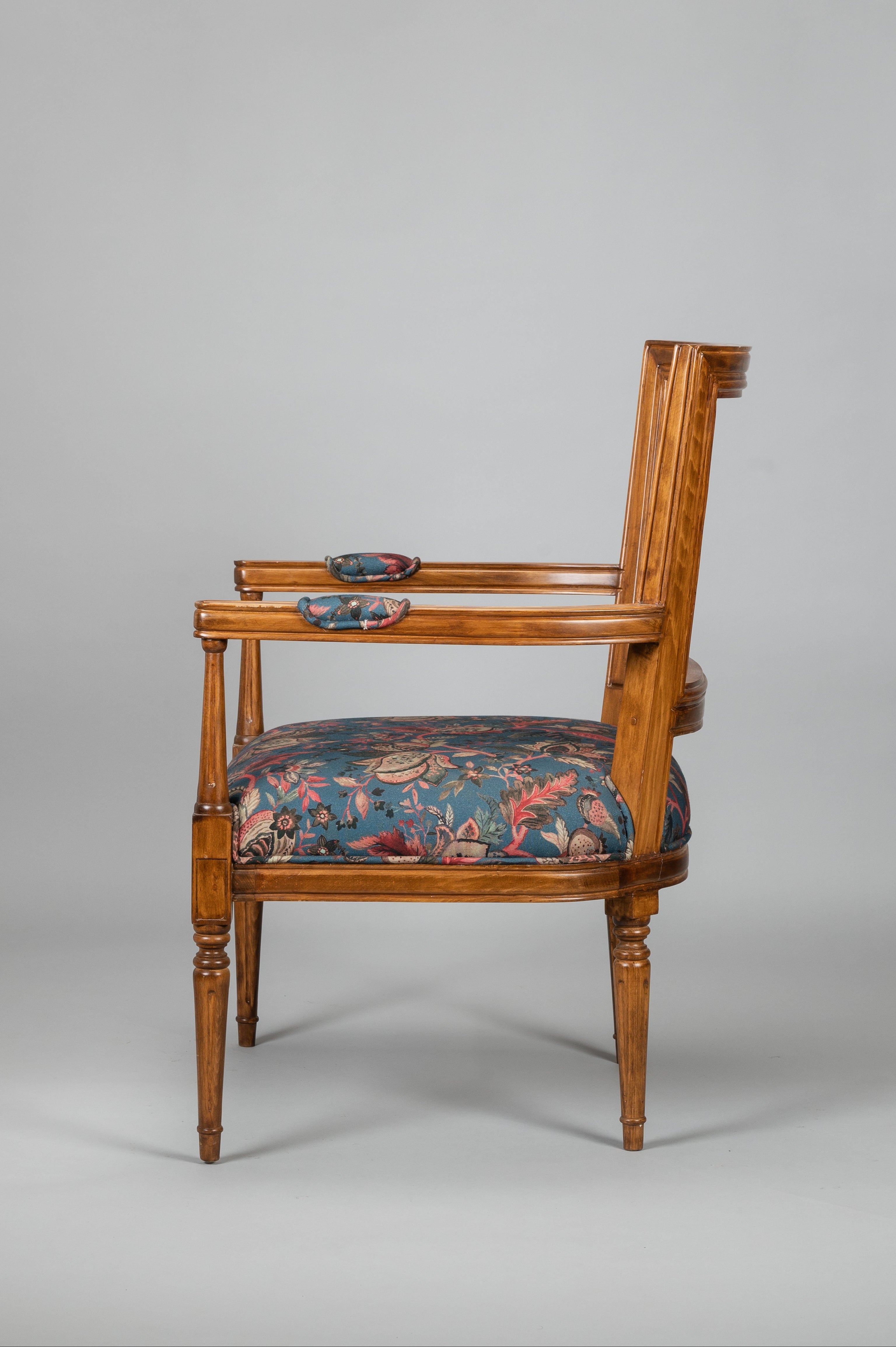 Wooden armchair with floral patterned seat on a gray background