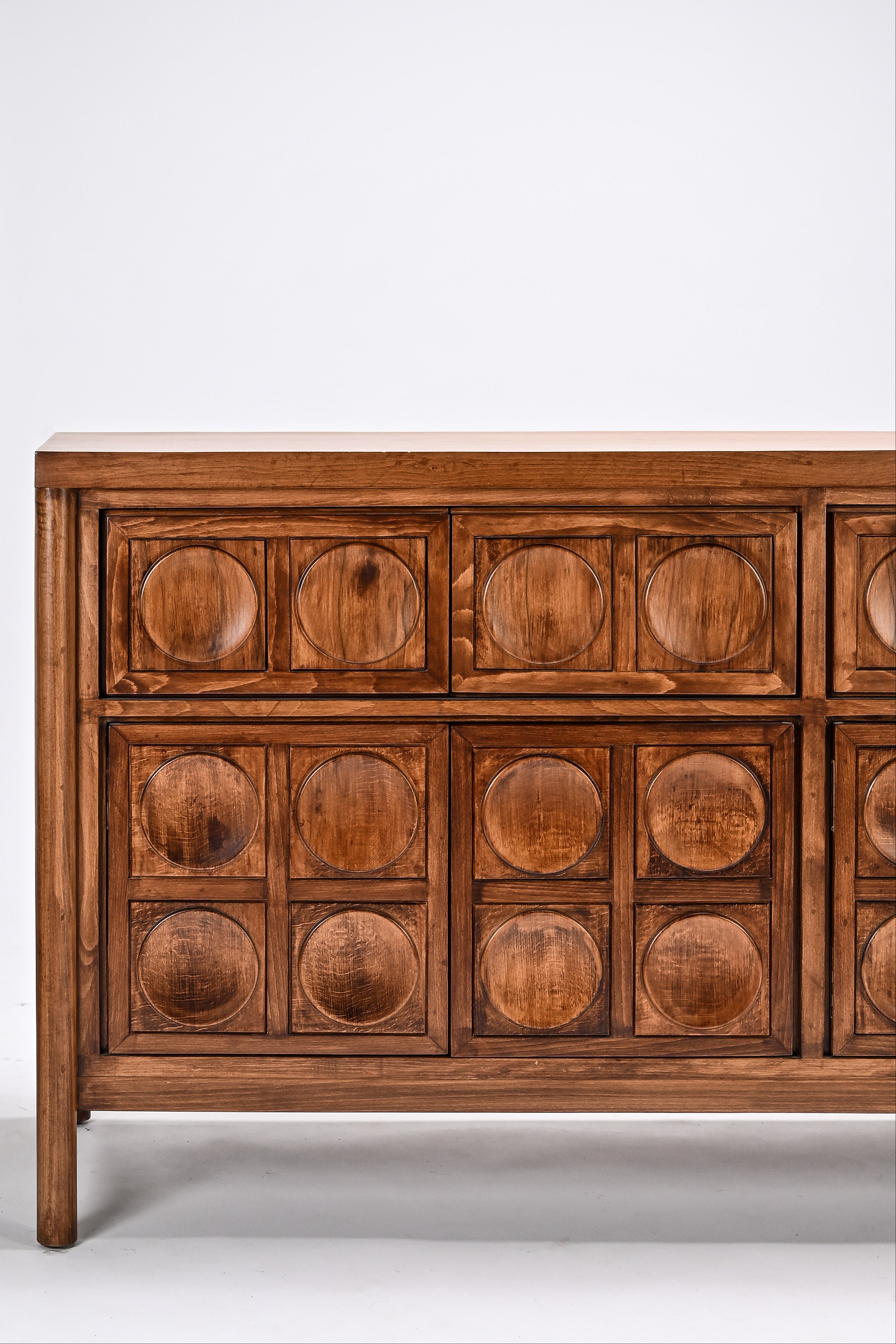 Wooden dresser with circular patterns on a white background
