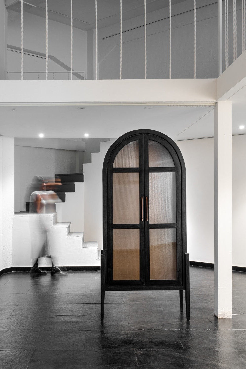 Modern interior with a black framed mirror and staircase in the background