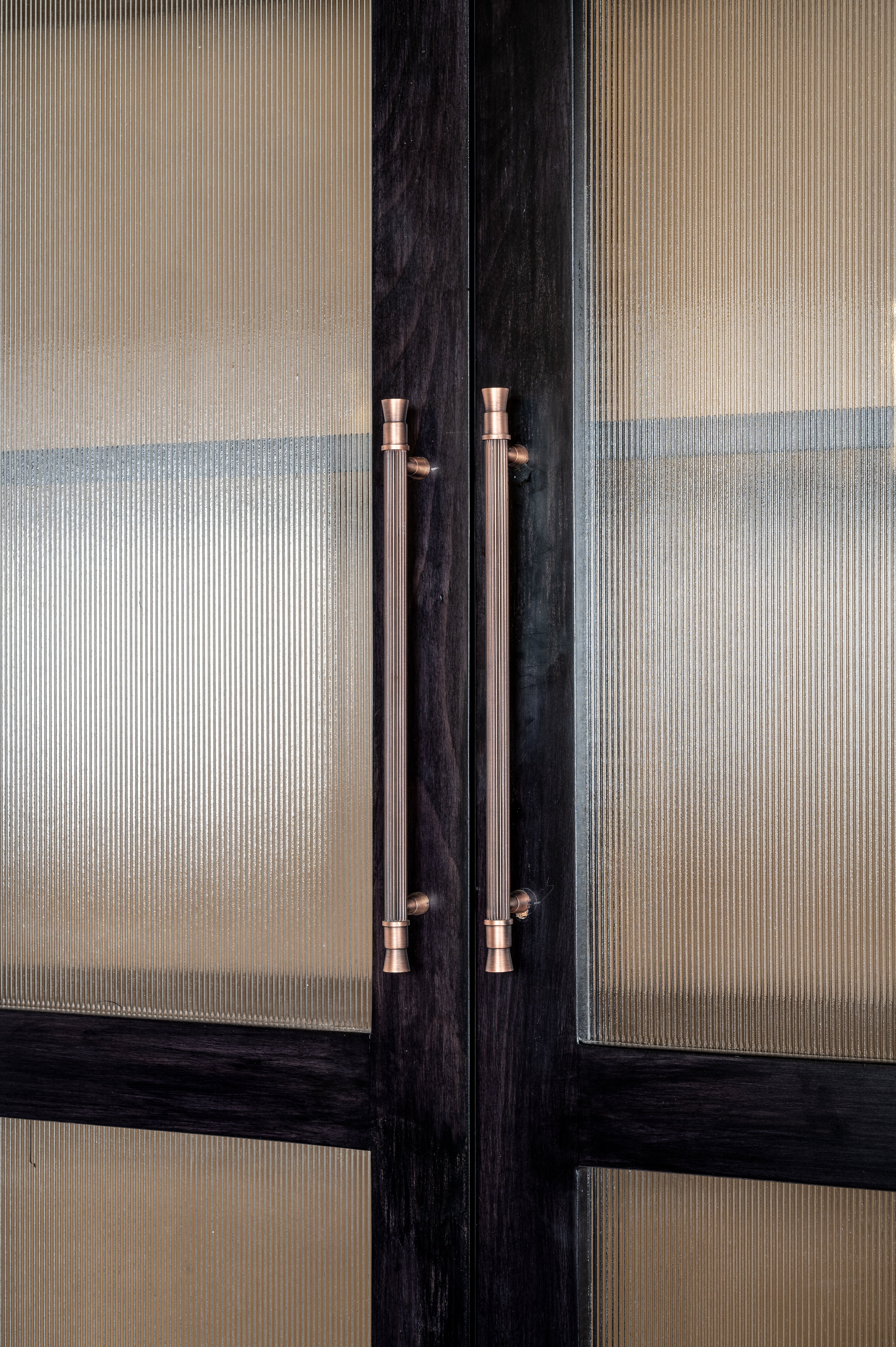 Glass door with bronze handles and black frame