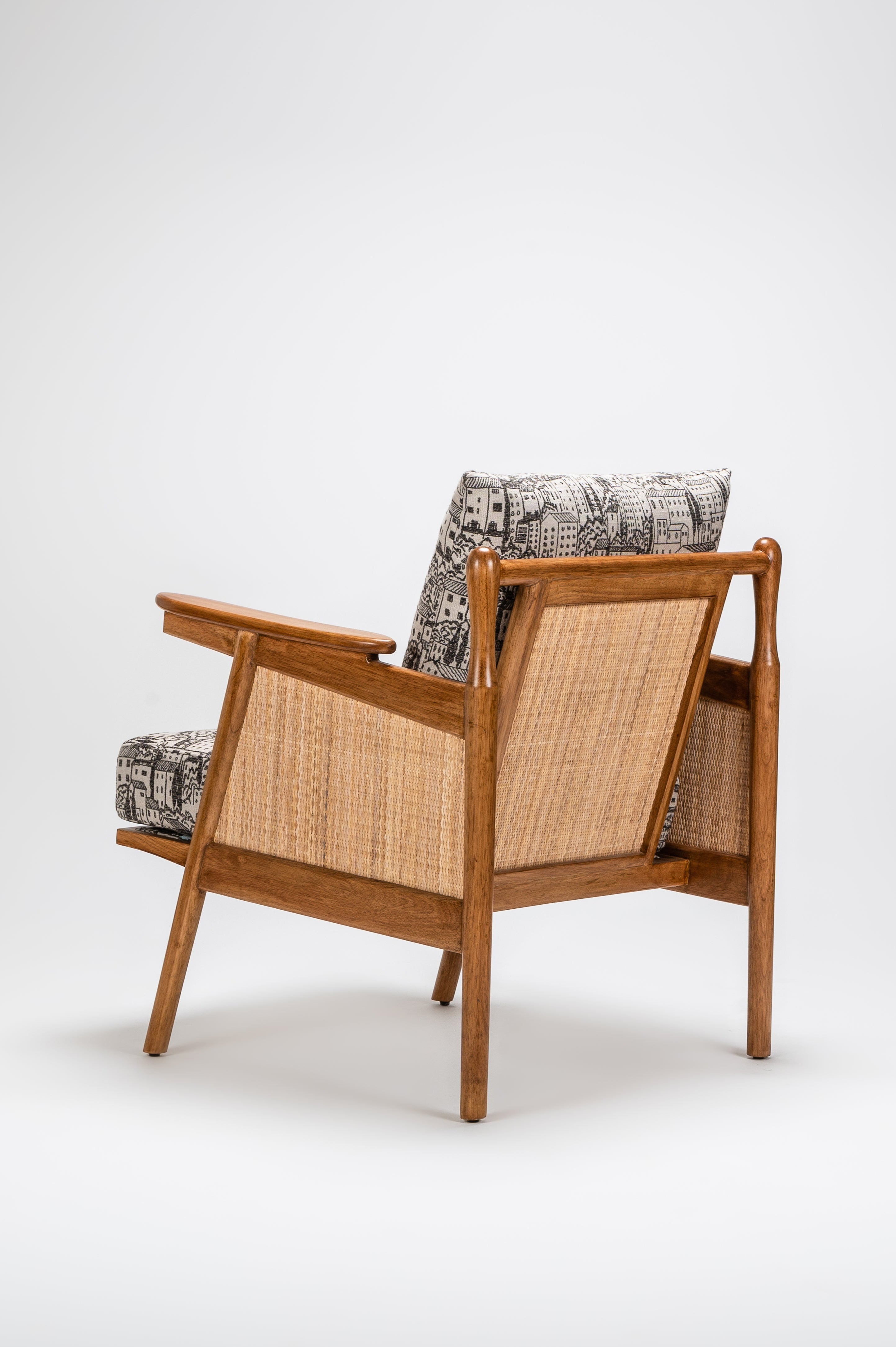 Wooden armchair with woven backrest and patterned cushions on a white background