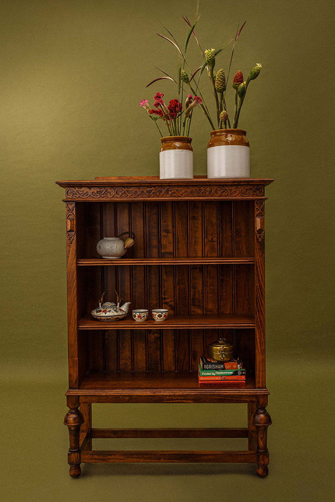 Wooden bookshelf with decorative items against a green background