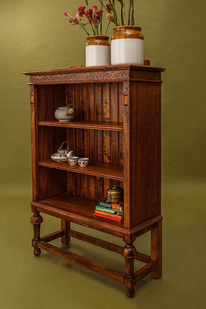 Wooden bookshelf with decorative items against a green background