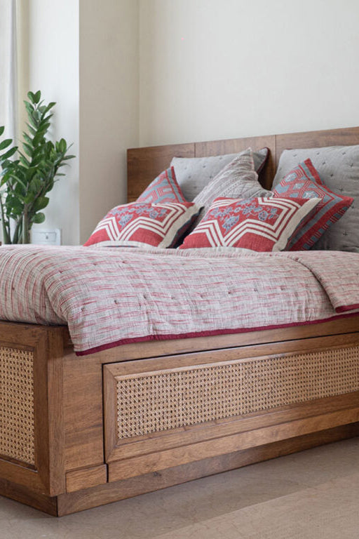 Wooden bed with wicker accents and decorative pillows in a bedroom setting.