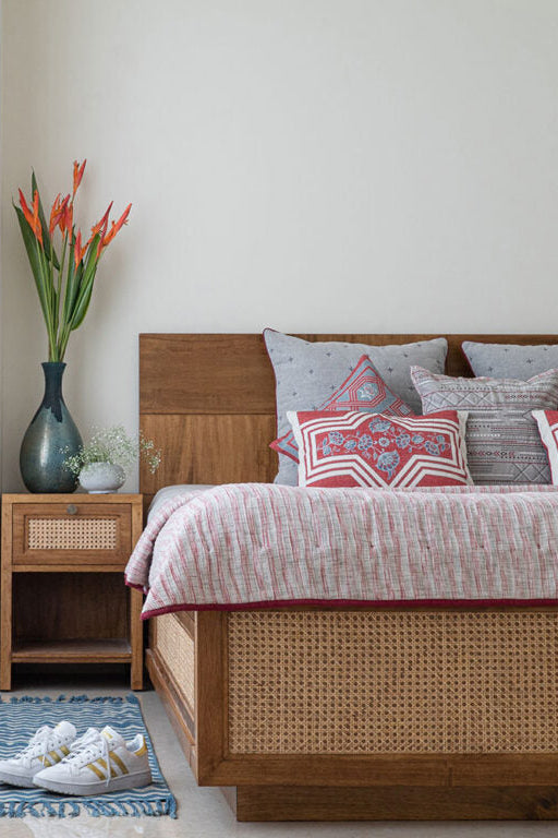 Bedroom with wooden bed, floral arrangement, and nightstand.