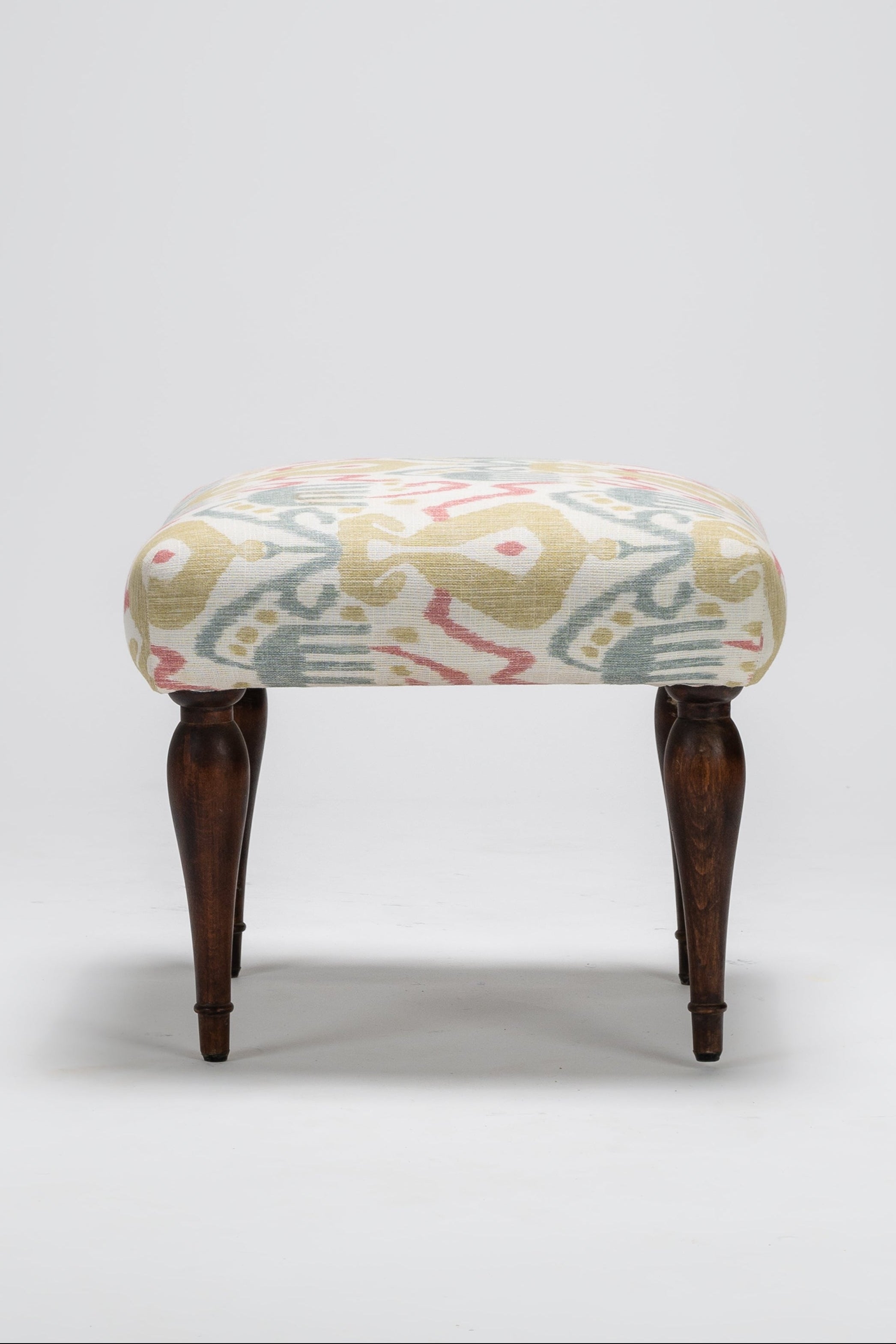 Small ottoman with a patterned cushion on a white background