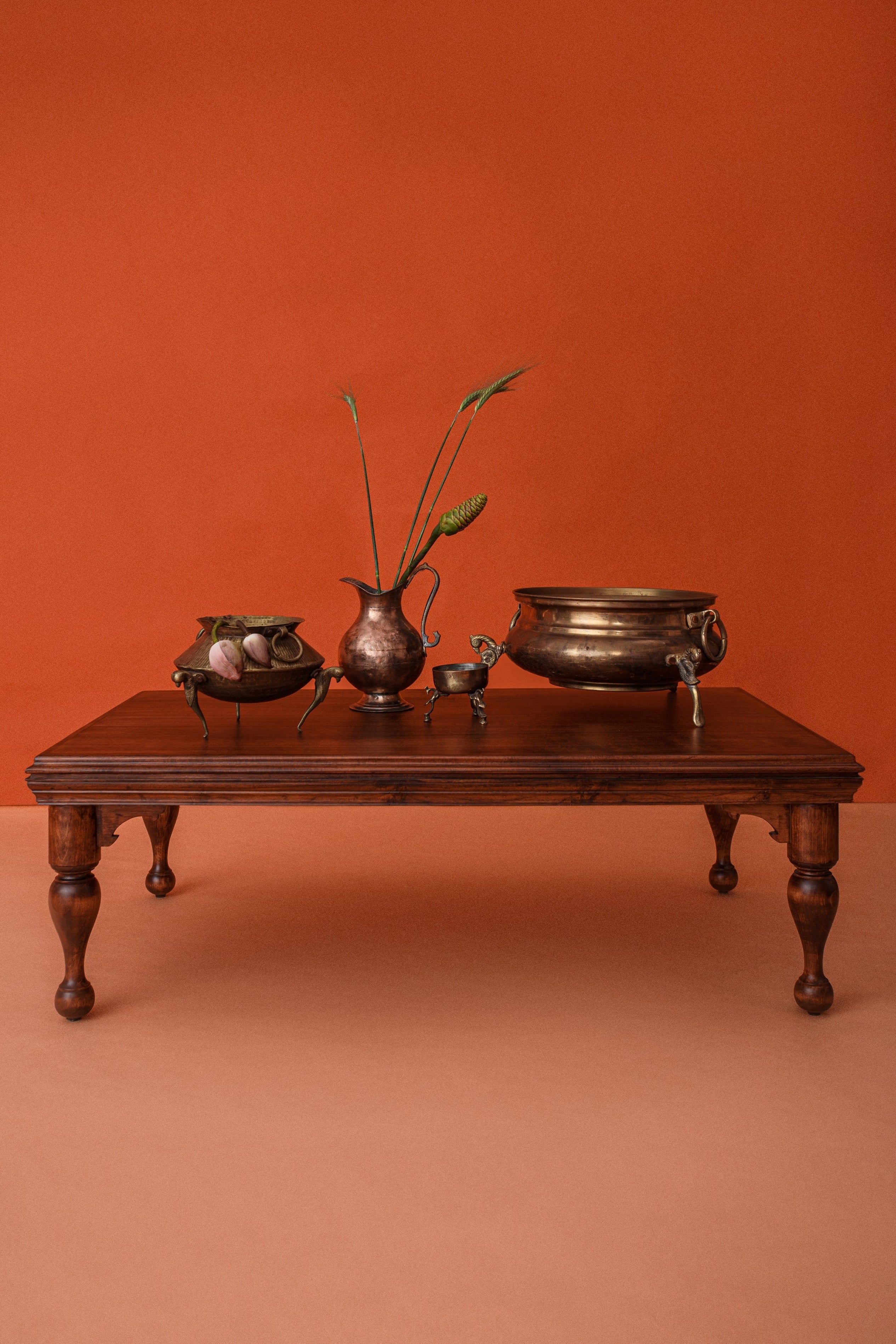 Wooden table with decorative items against an orange wall