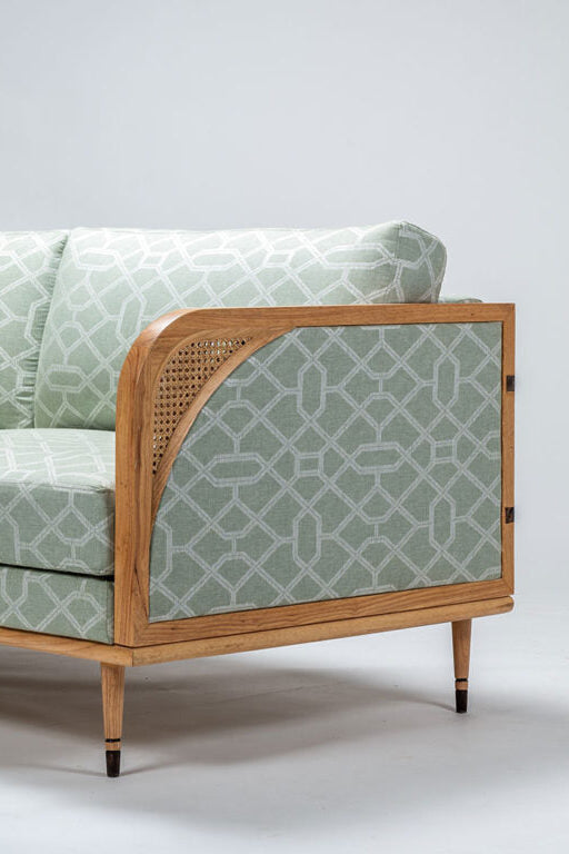 Sofa with green patterned fabric and wooden frame on a white background