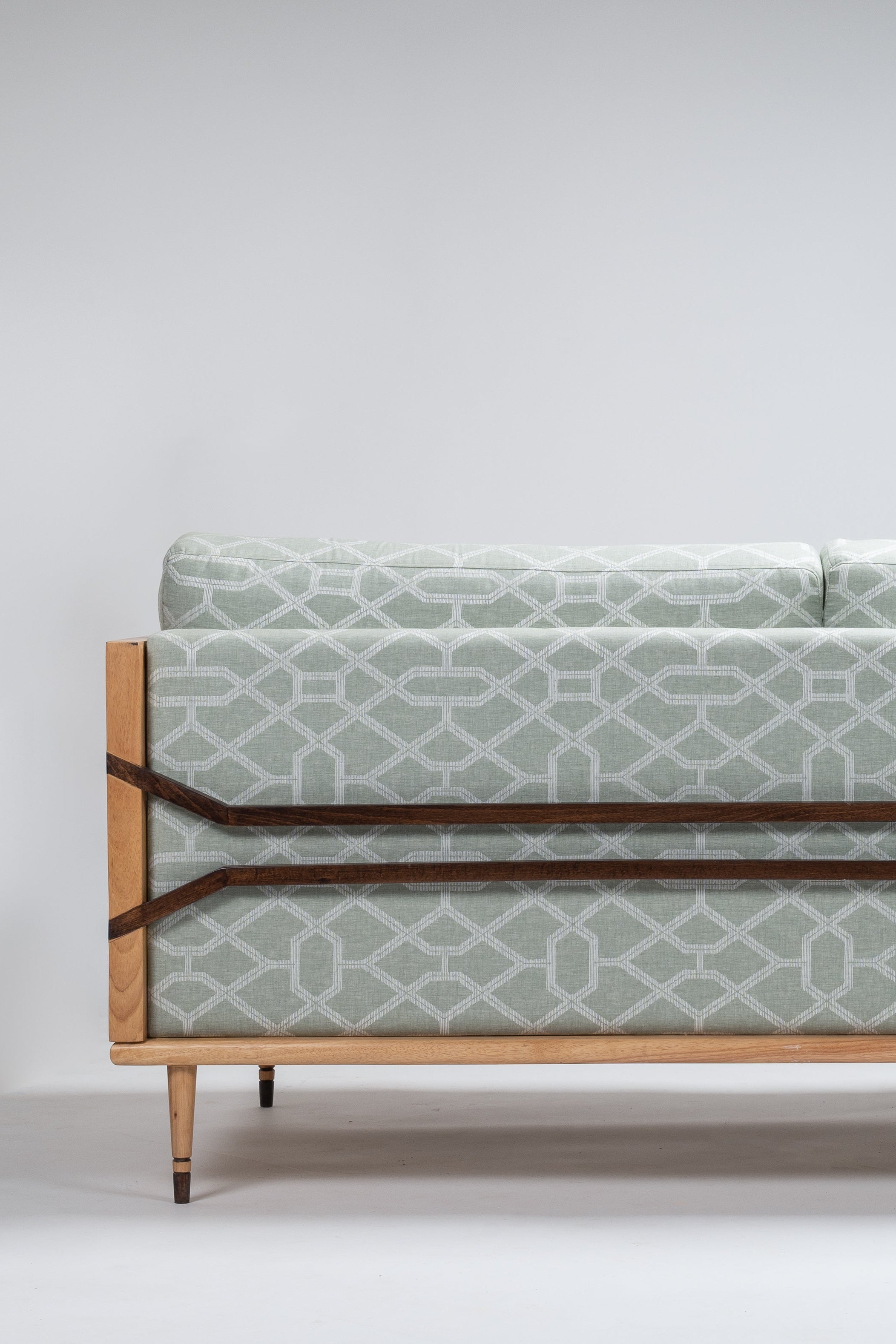 Sofa with patterned fabric and wooden frame on a white background