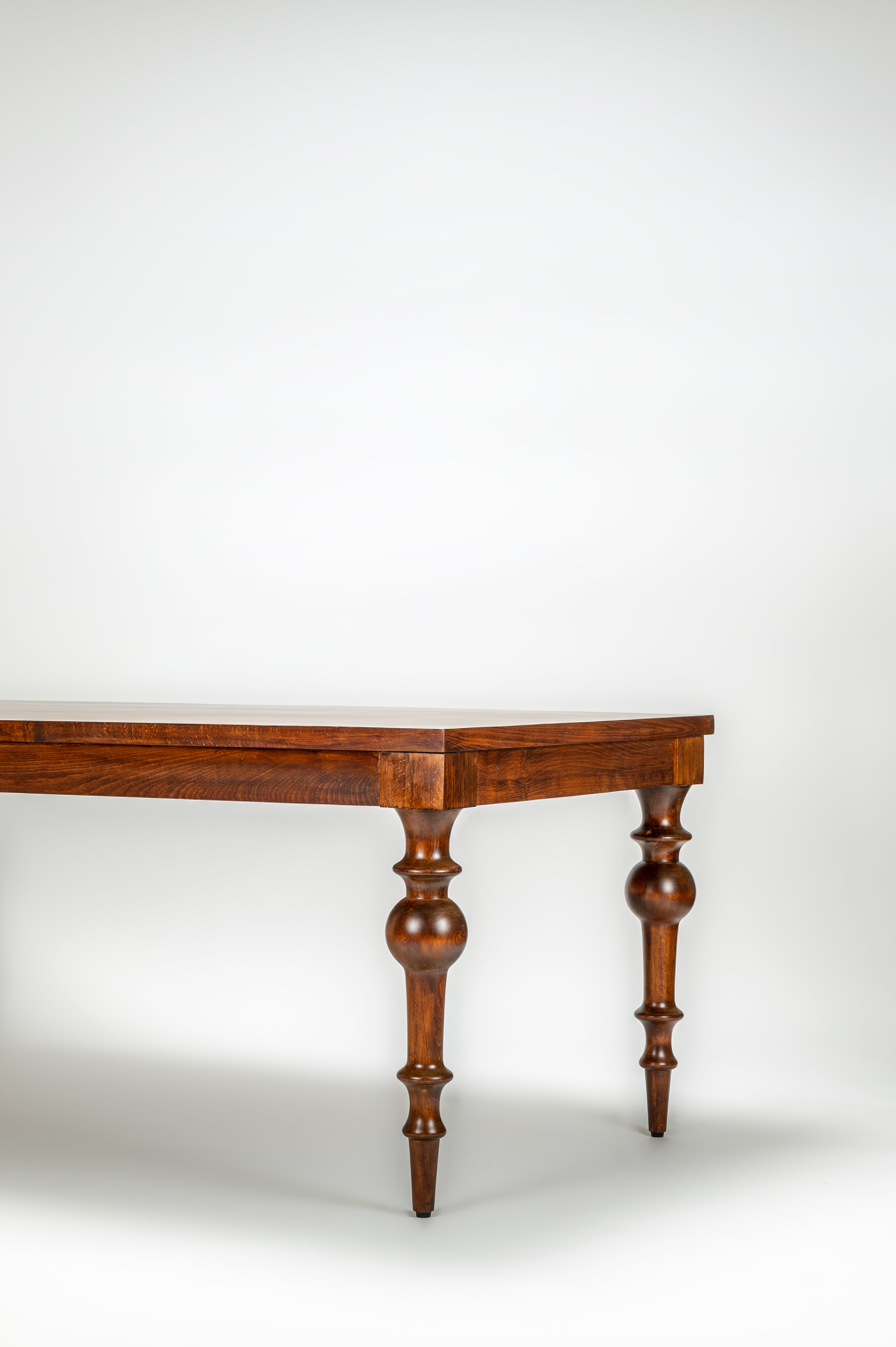 Wooden table with curved top and turned legs on a white background