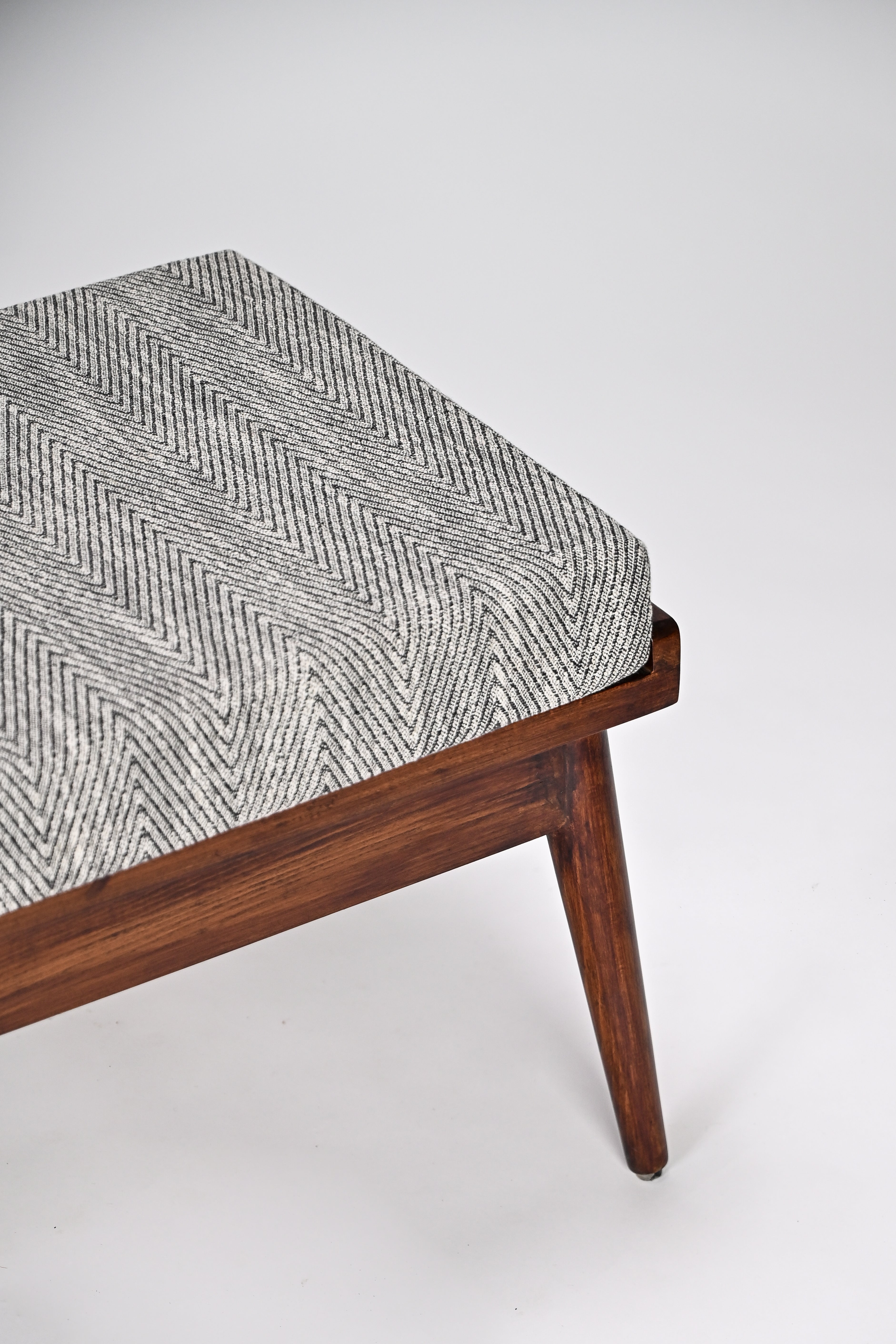 Wooden bench with a patterned cushion on a white background