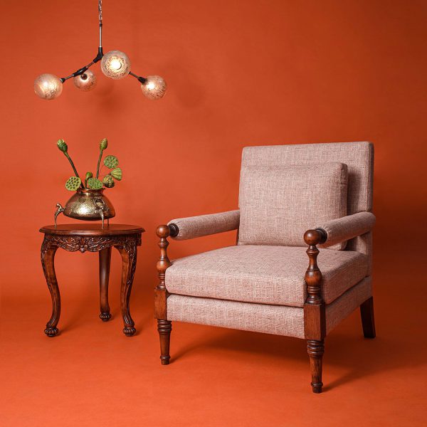 Vintage armchair and side table against an orange wall with a modern chandelier.