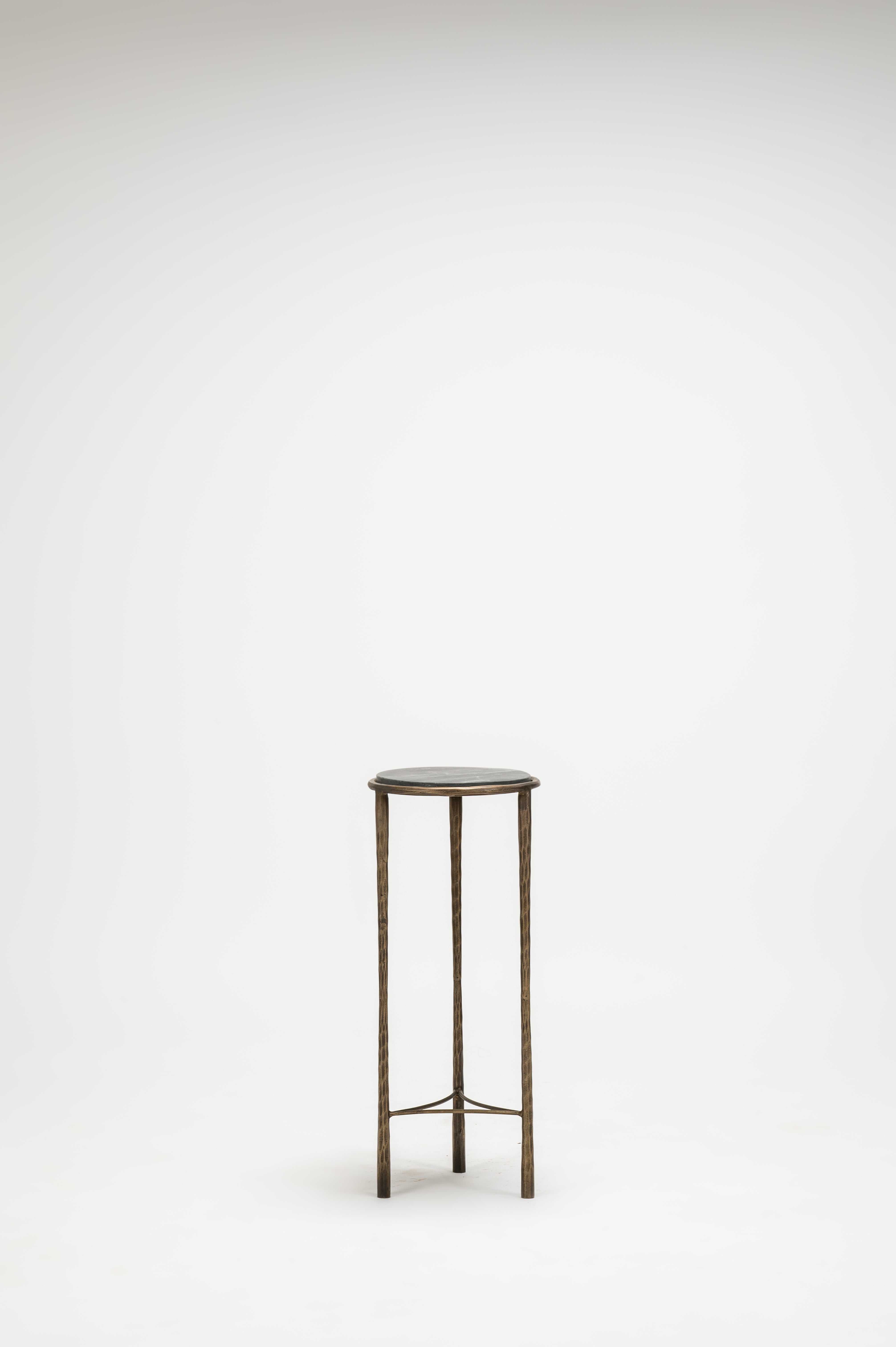 Small round table with a black top and bronze legs on a white background