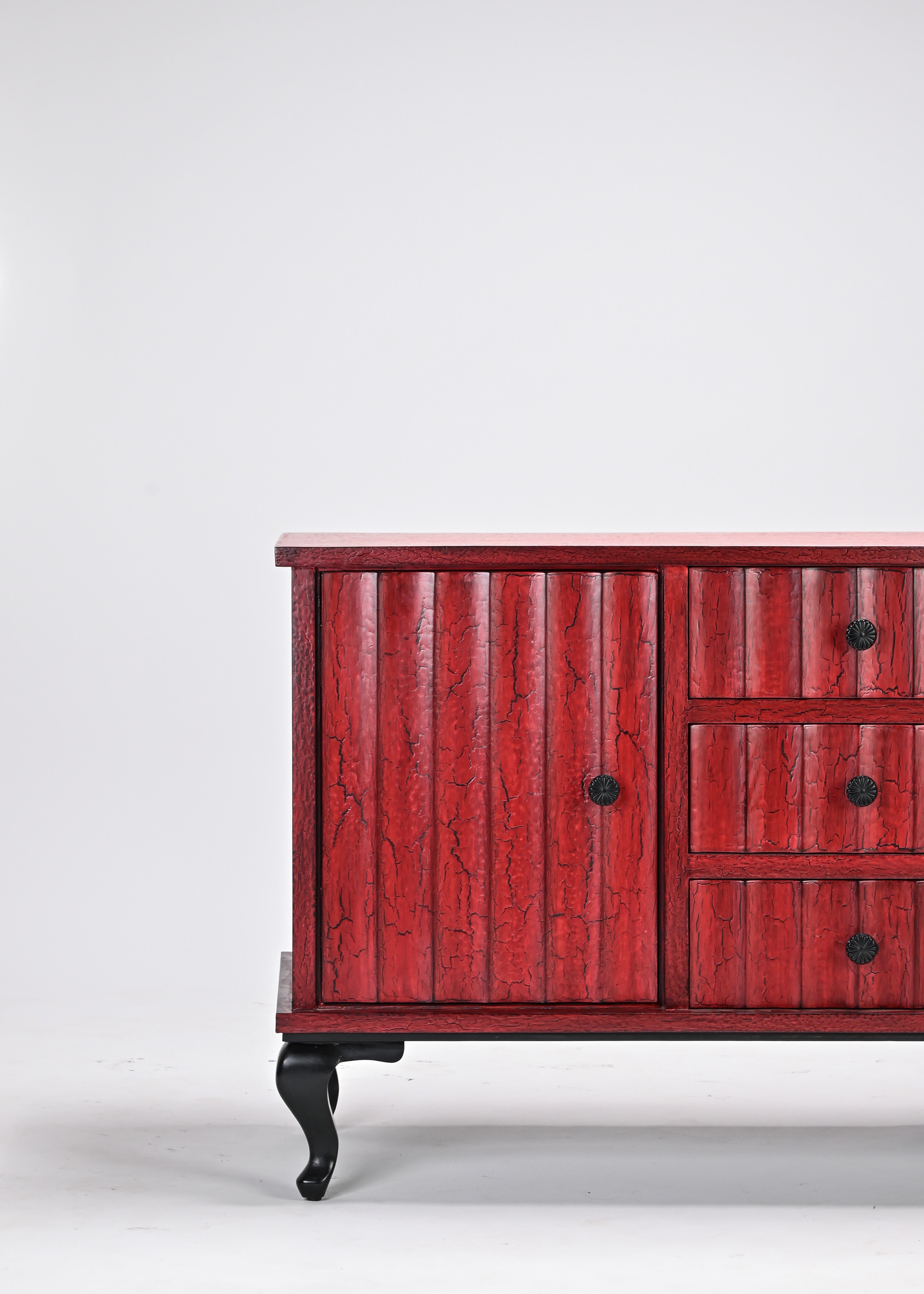 Red wooden dresser with black knobs on a white background