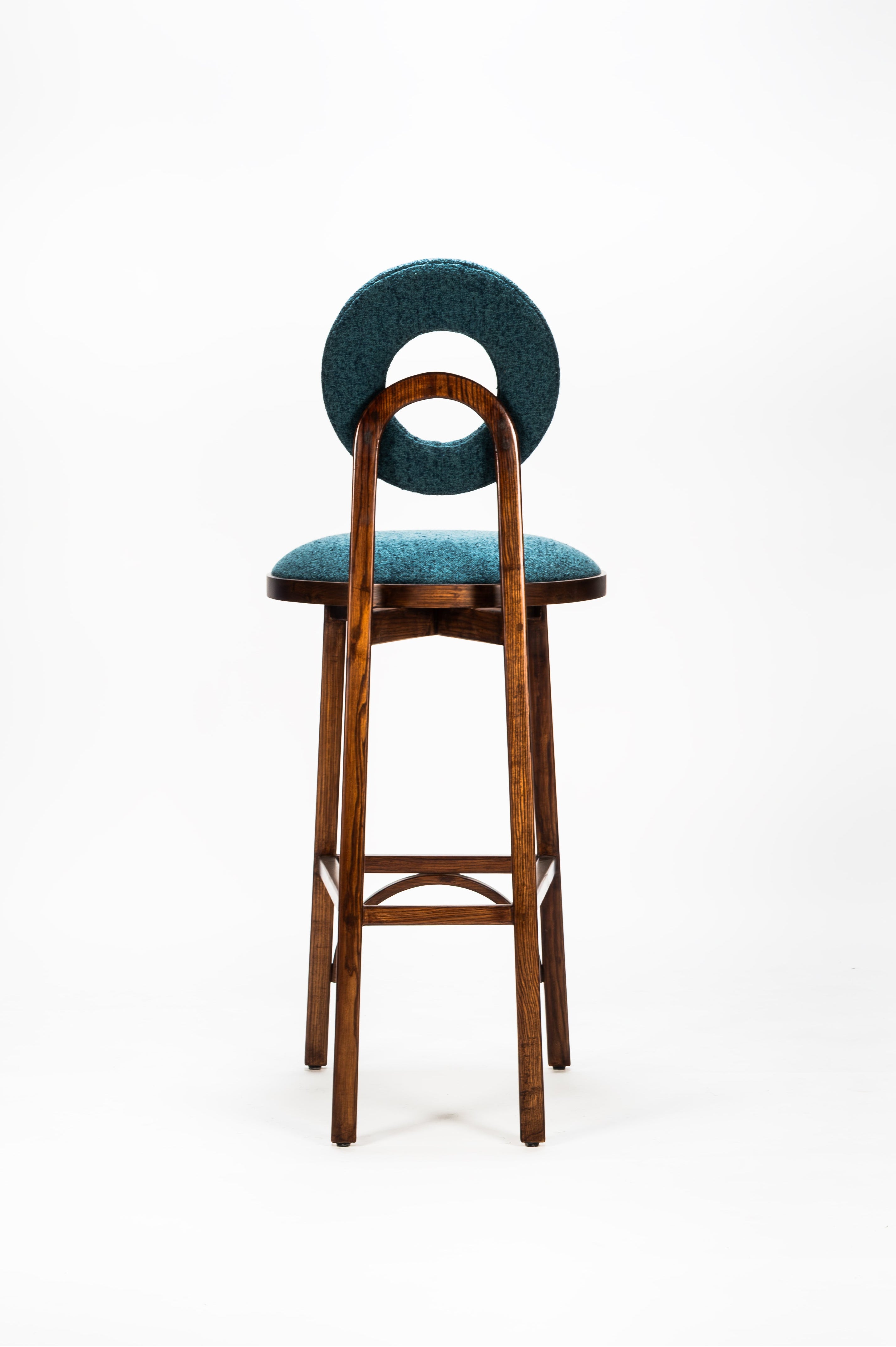 Bar stool with green cushioned seat and backrest on a white background