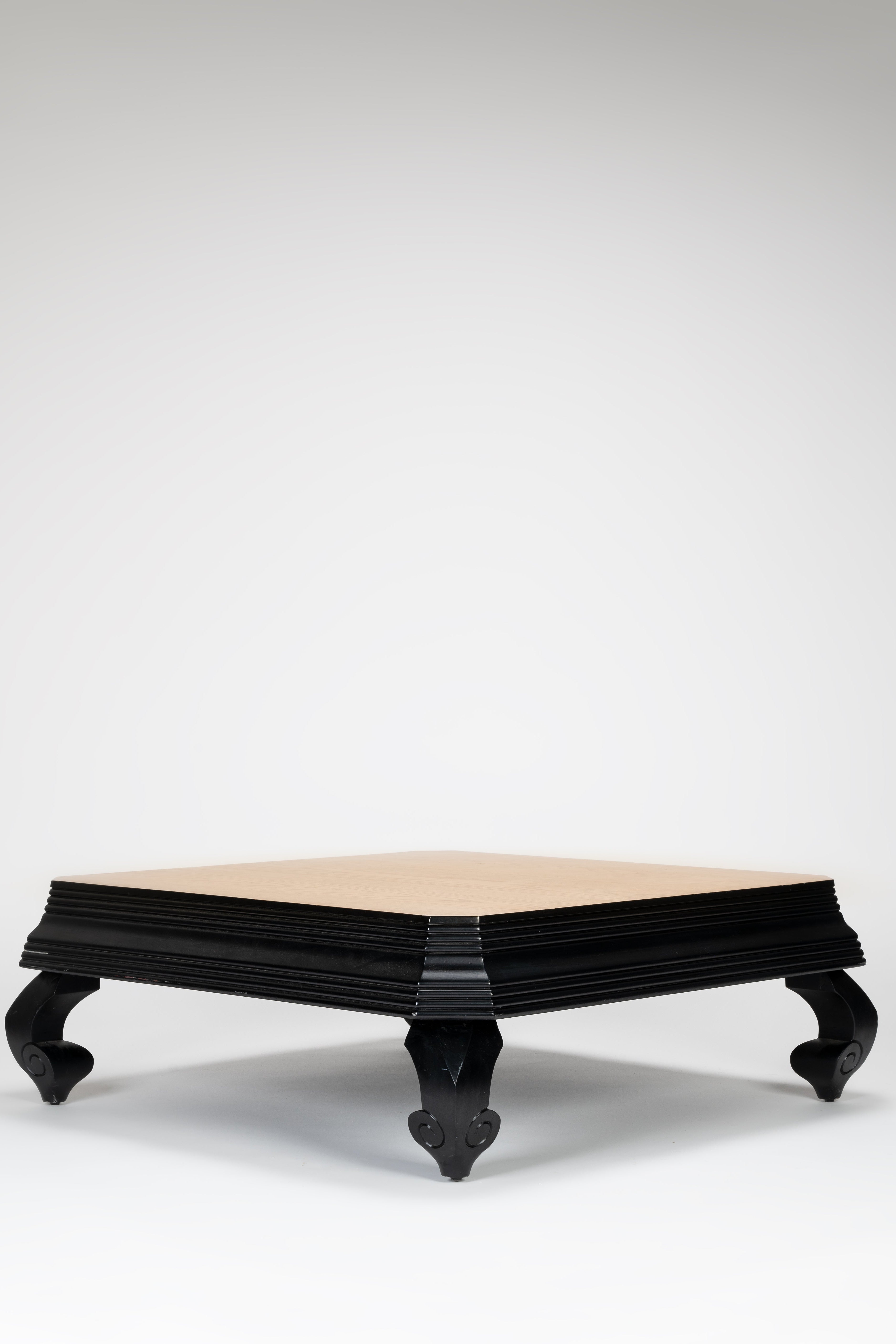 Round coffee table with black base and beige top on a white background