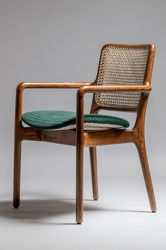 Wooden chair with wicker backrest and green cushion on a gray background