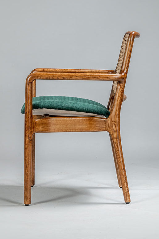 Wooden chair with green cushion on a gray background
