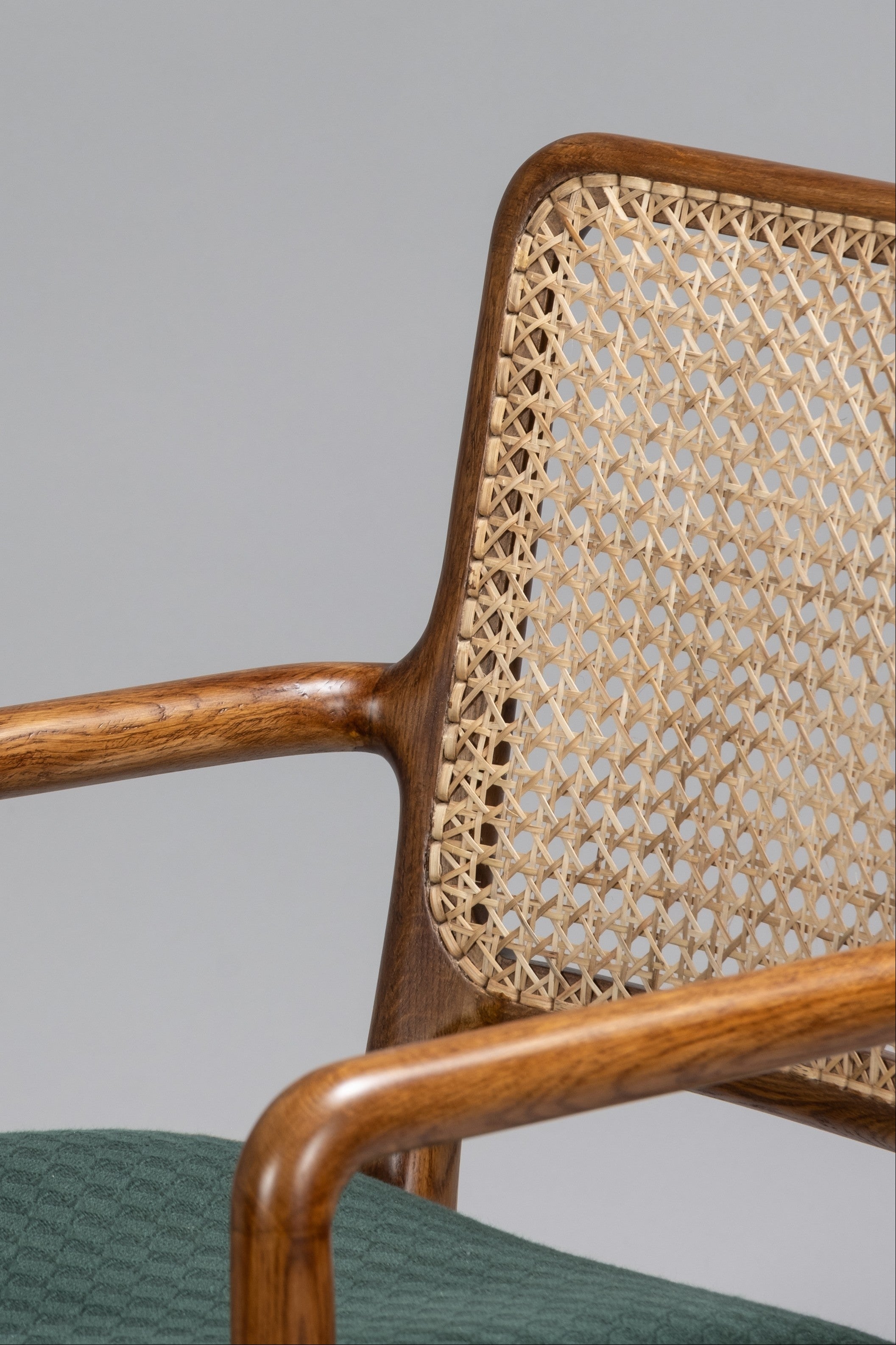 Chair with wicker backrest and wooden armrests on a gray background