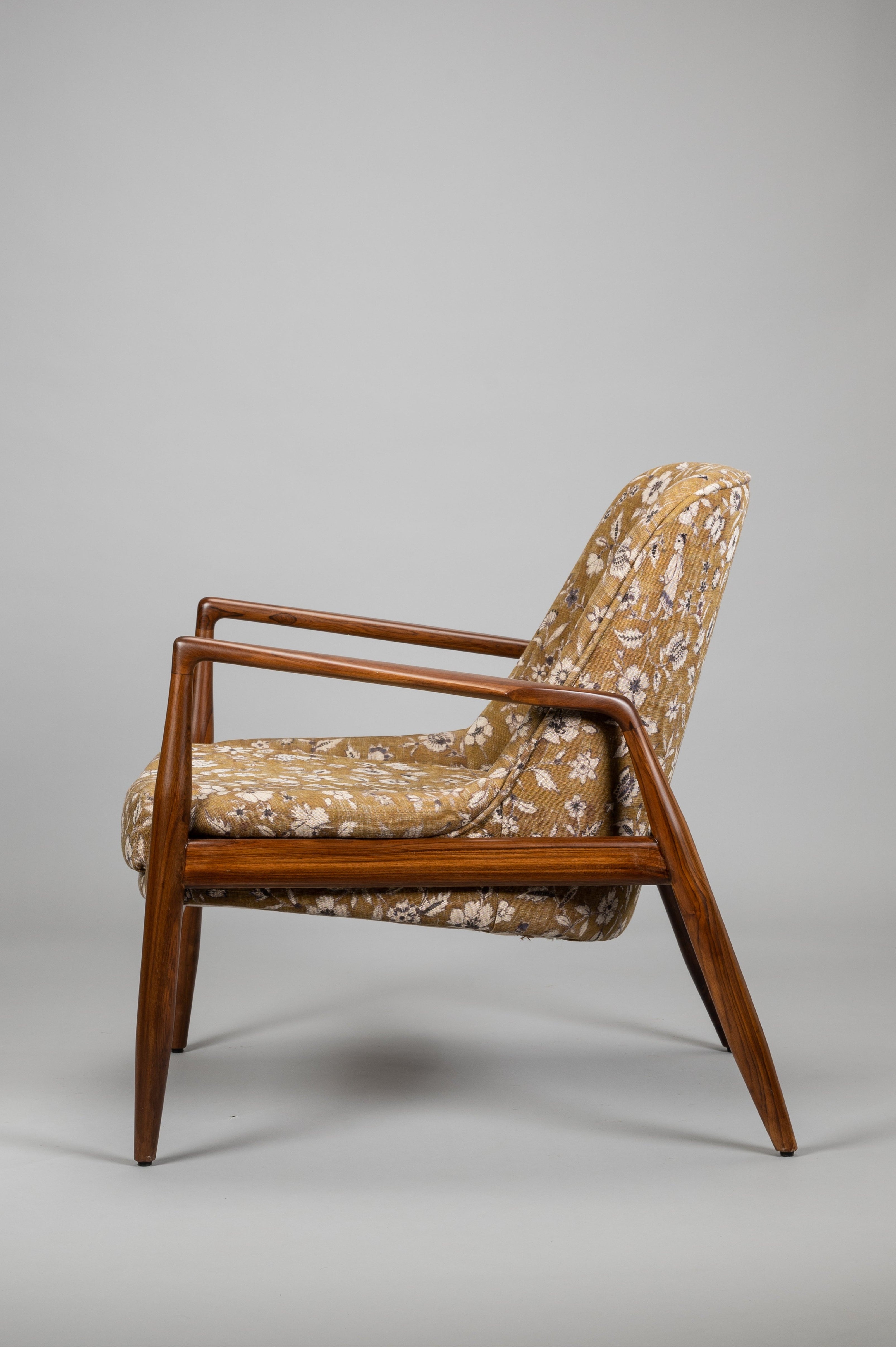 Vintage armchair with wooden frame and patterned fabric on a gray background