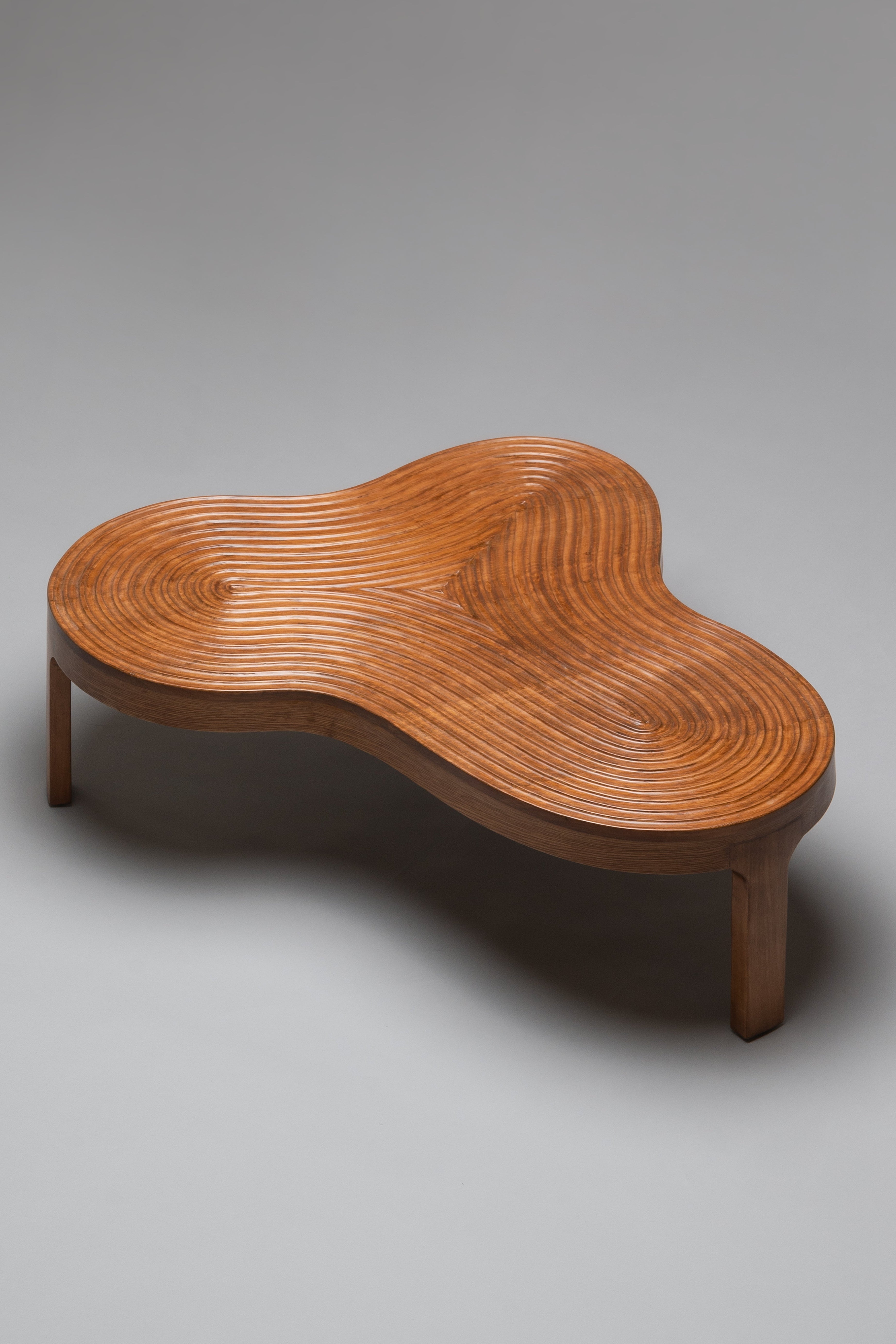 Wooden coffee table with wavy surface design on a gray background