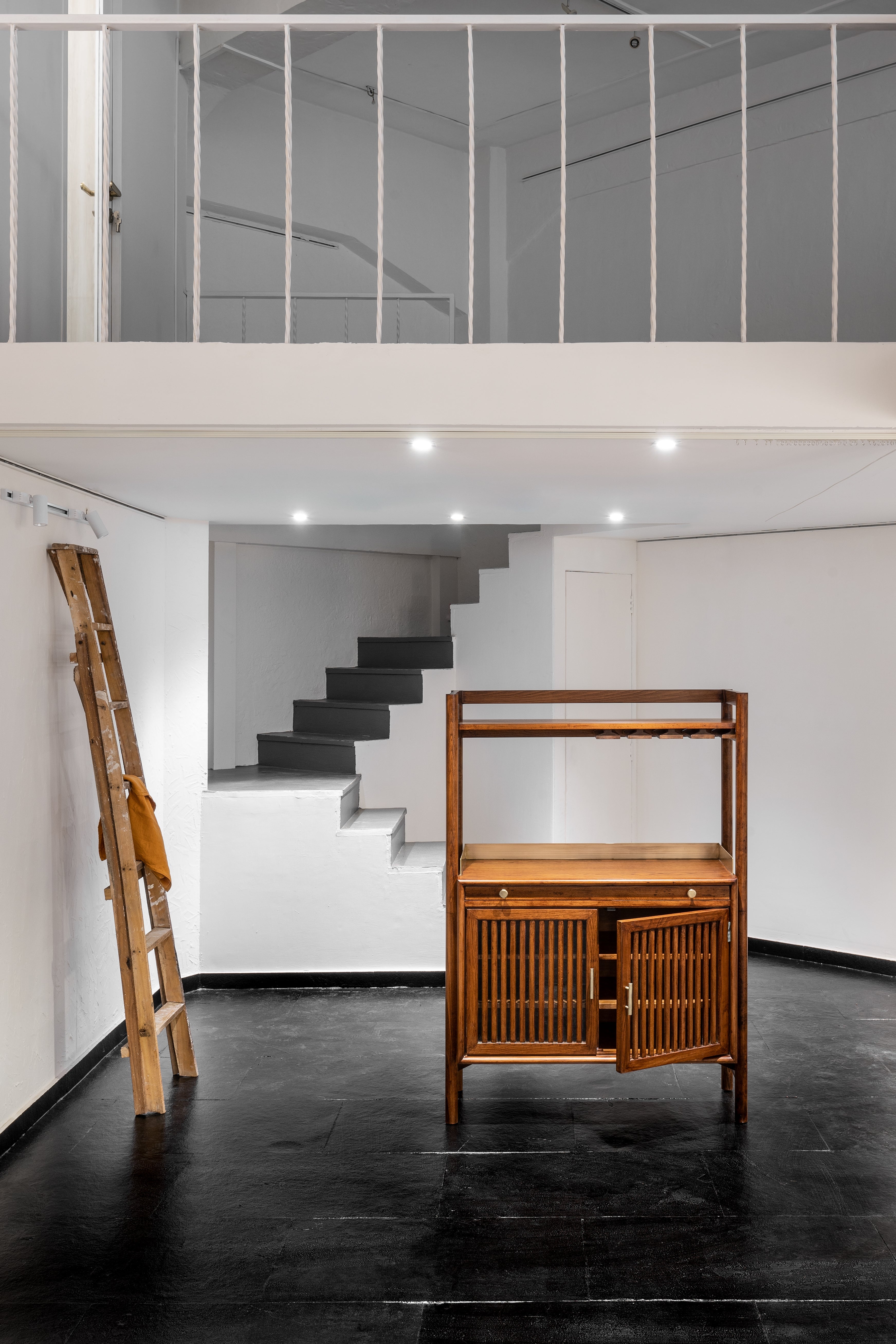 Modern interior with wooden cabinet, black staircase, and glass wall.