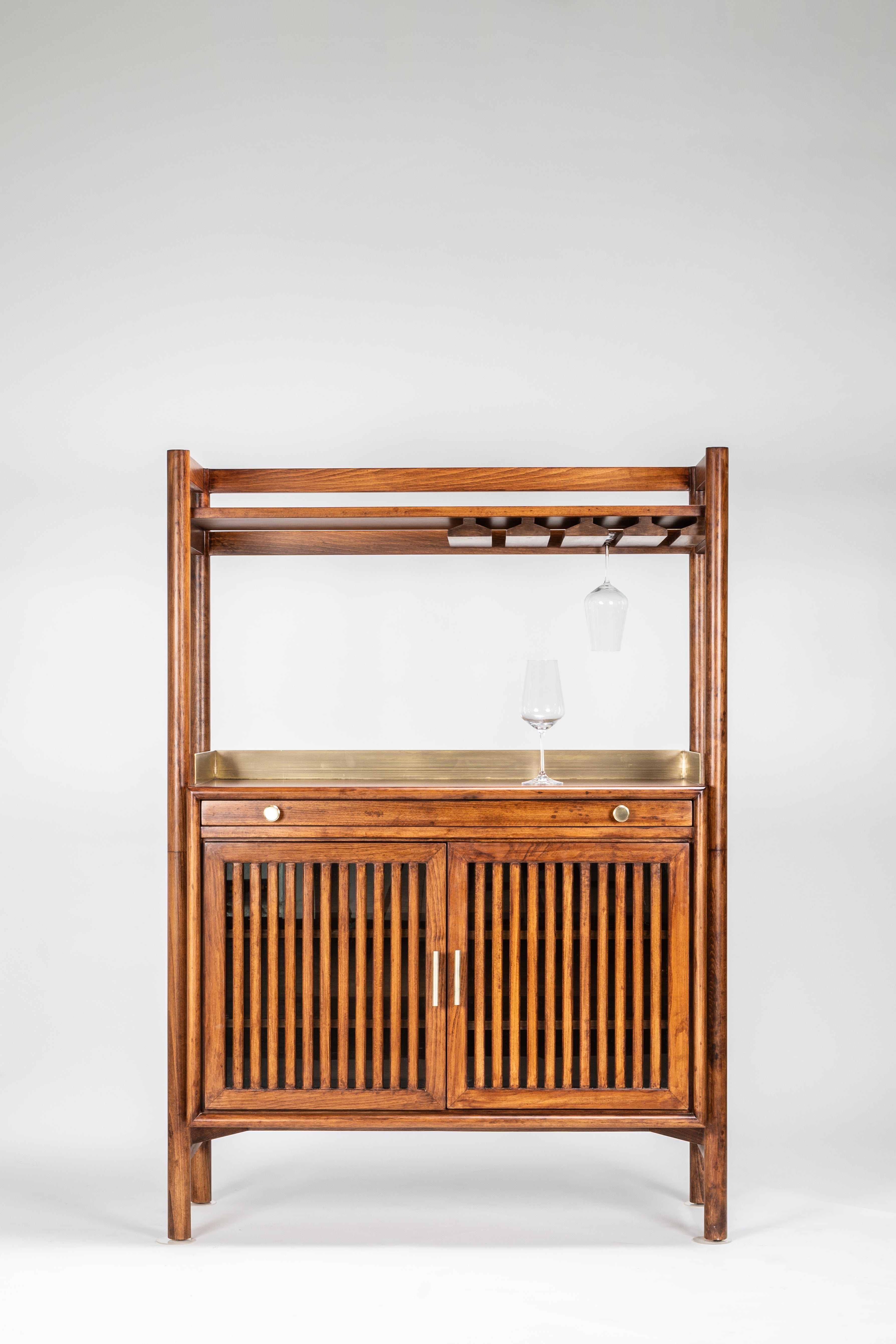 Wooden bar cart with glass shelves and wine rack on a white background