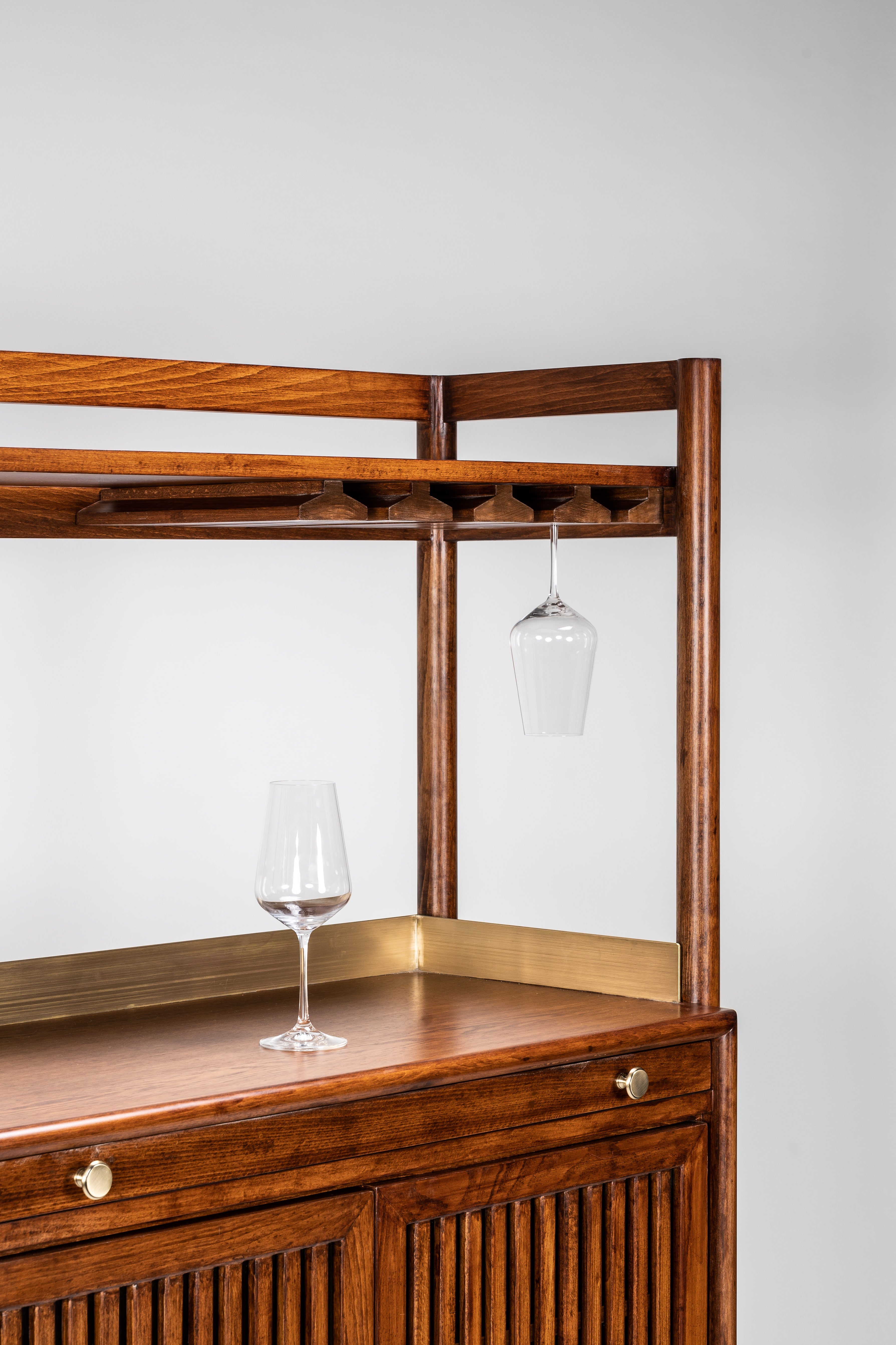 Wooden bar cabinet with wine glasses on a white background